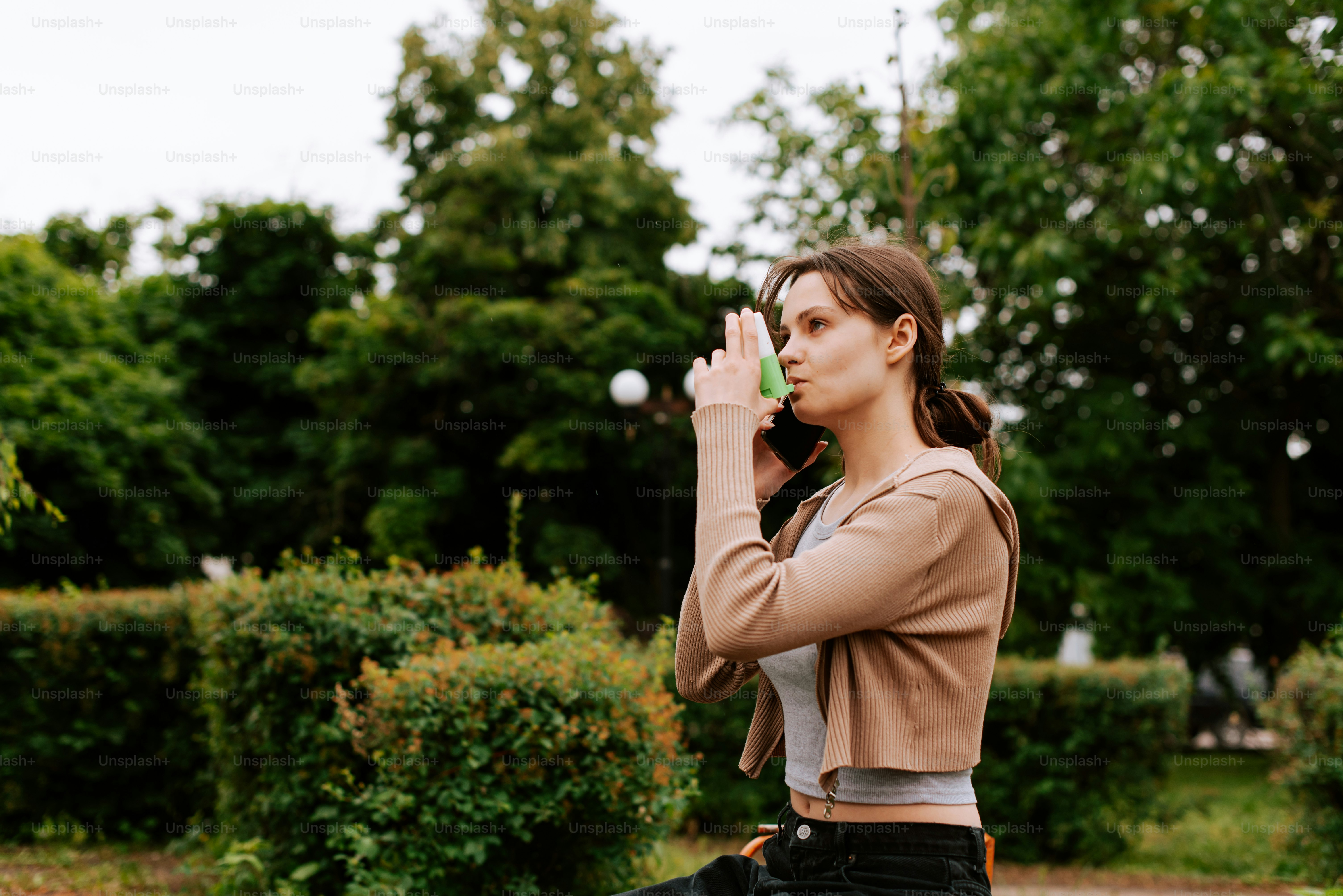 a woman standing in a park talking on a cell phone