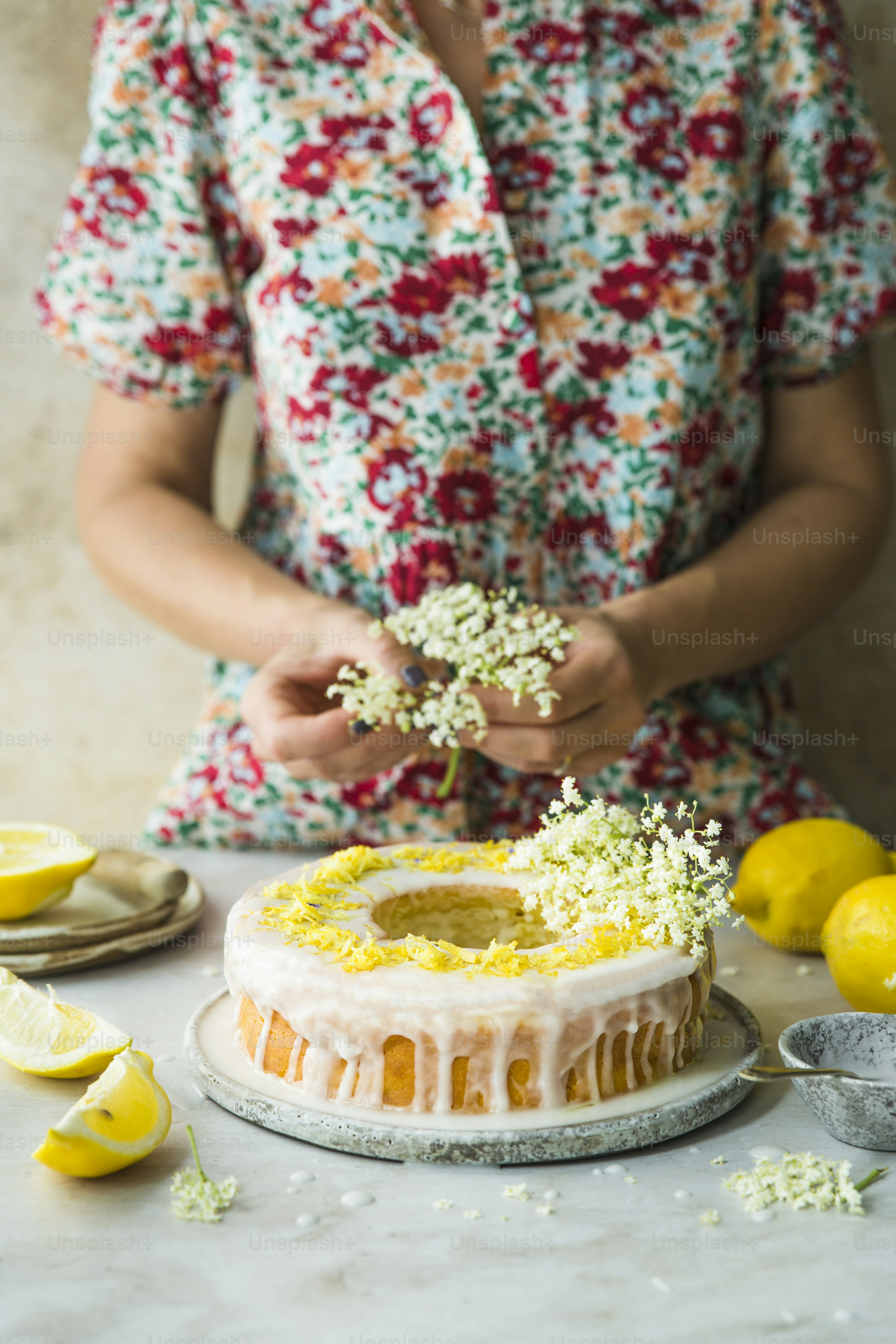 a woman is decorating a cake with flowers and lemons