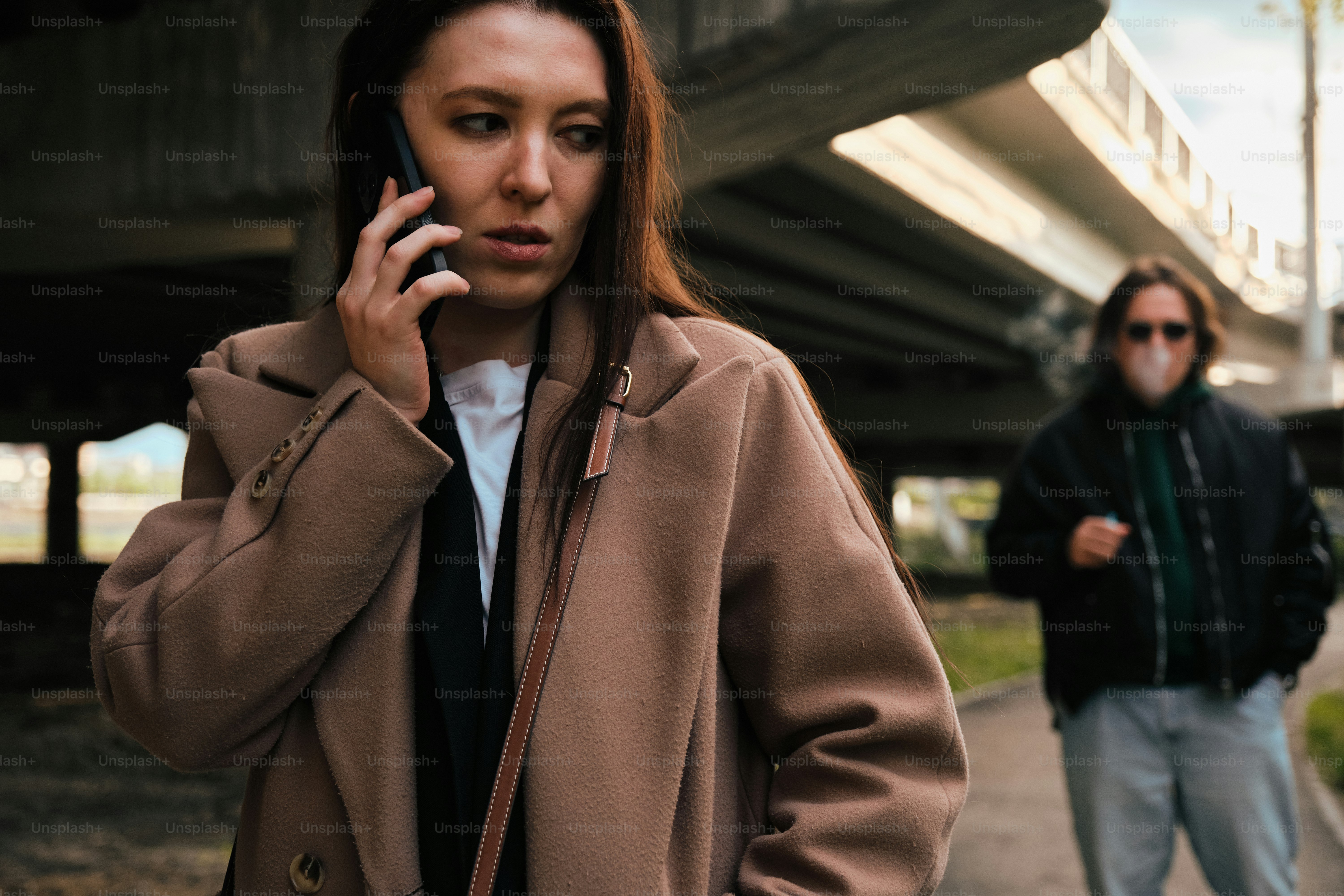 a woman talking on a cell phone while standing next to a man