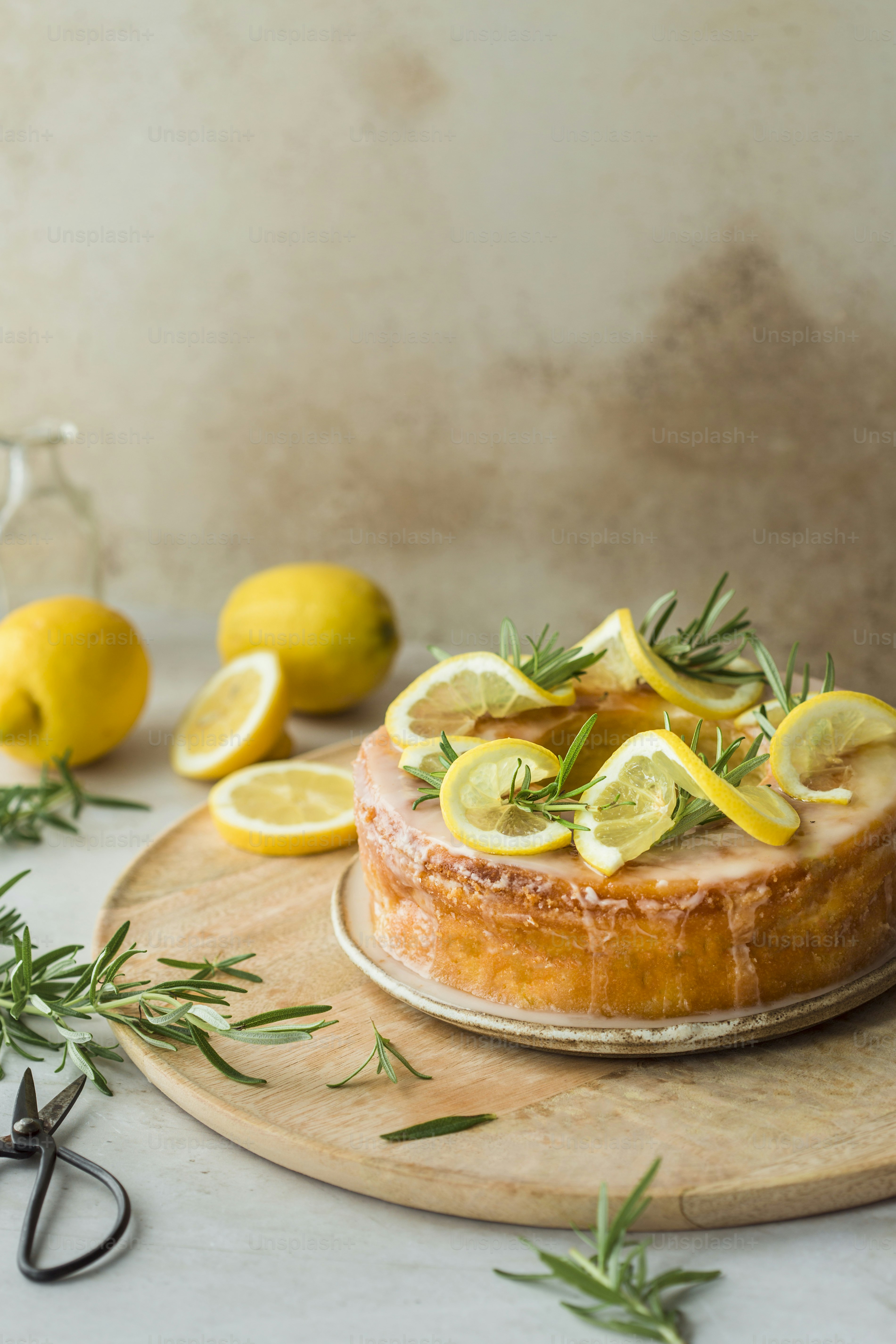 a cake with lemons and rosemary on a cutting board