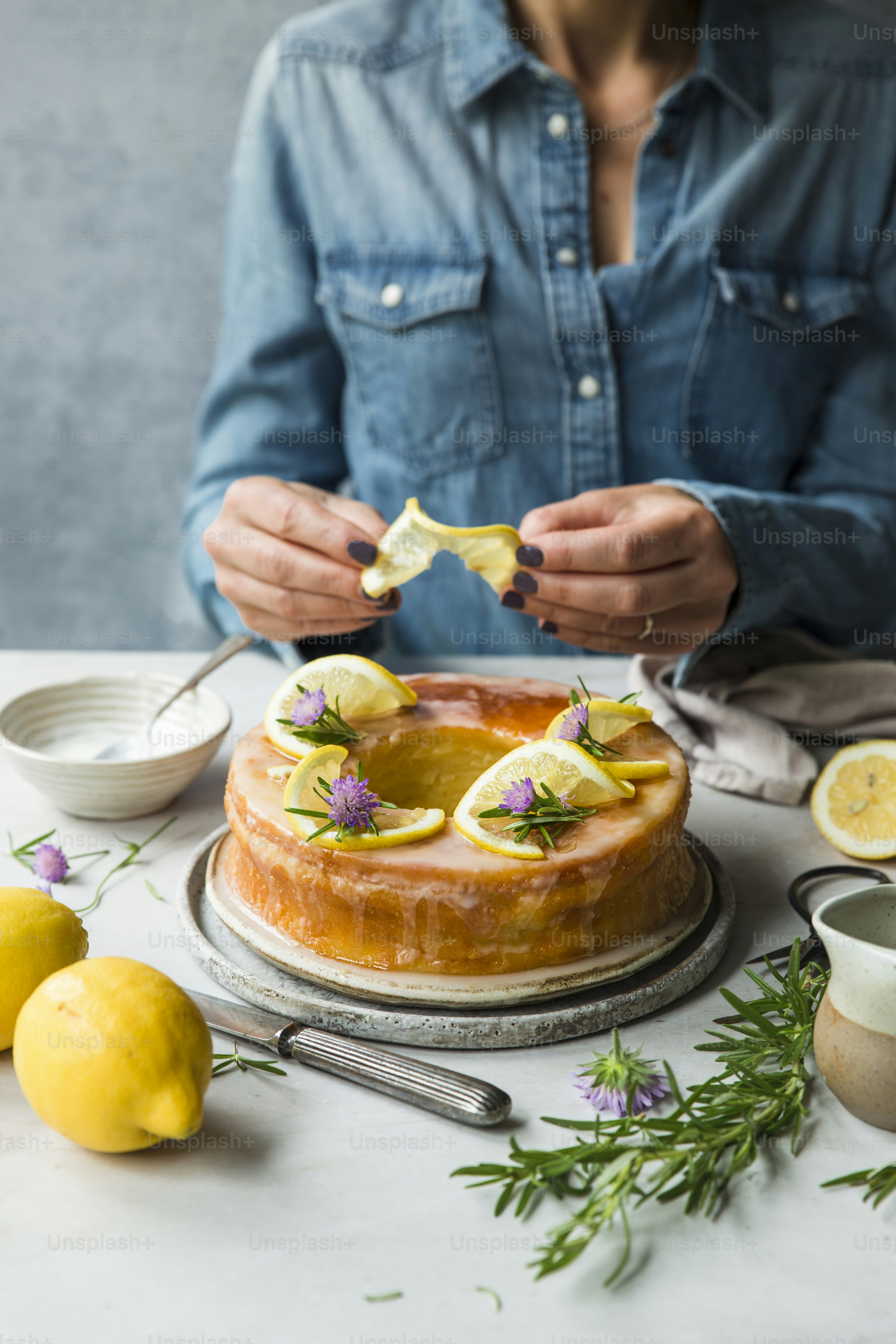 a woman is decorating a cake with lemons and herbs