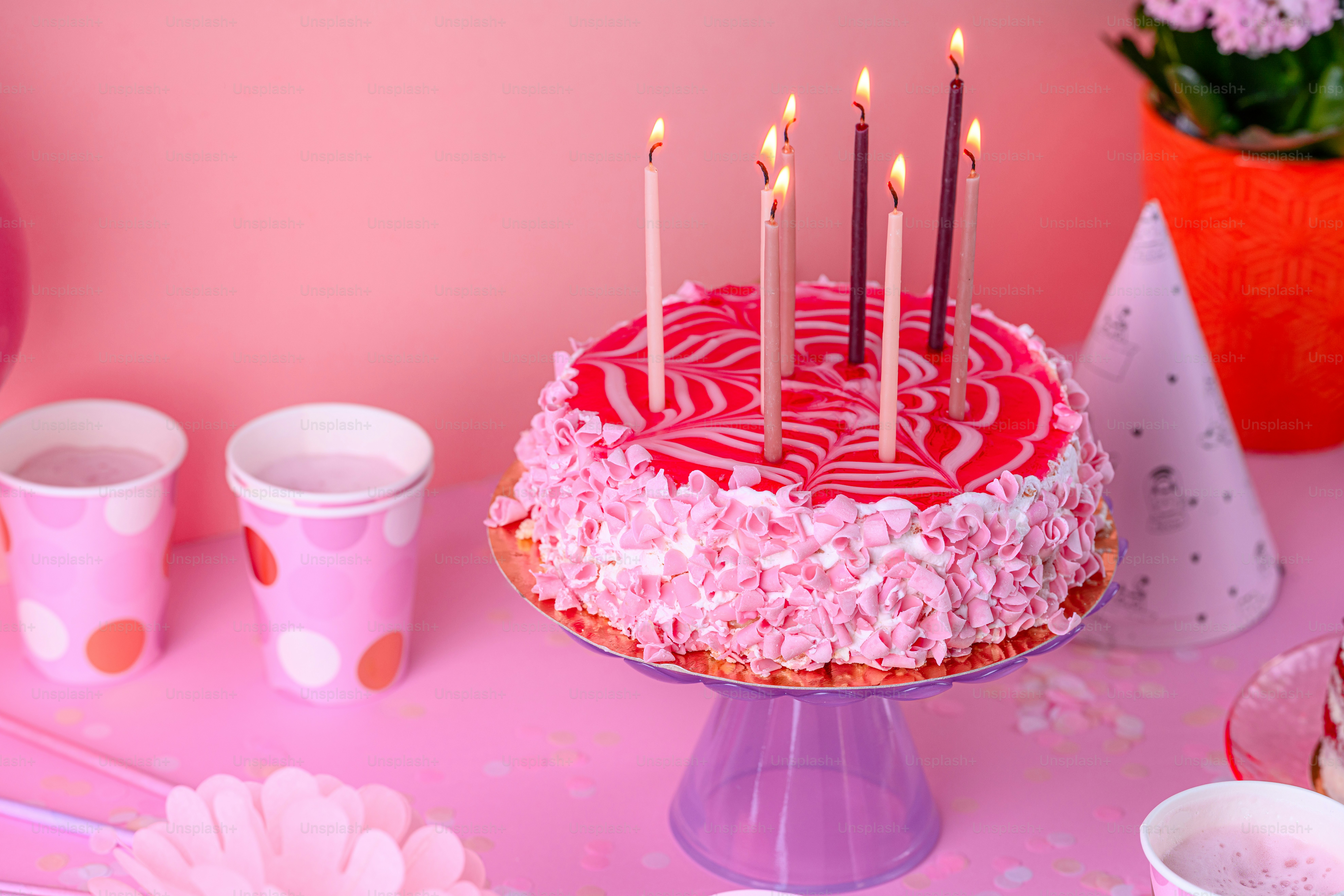 A birthday cake with pink frosting and lit candles photo – Birthday ...