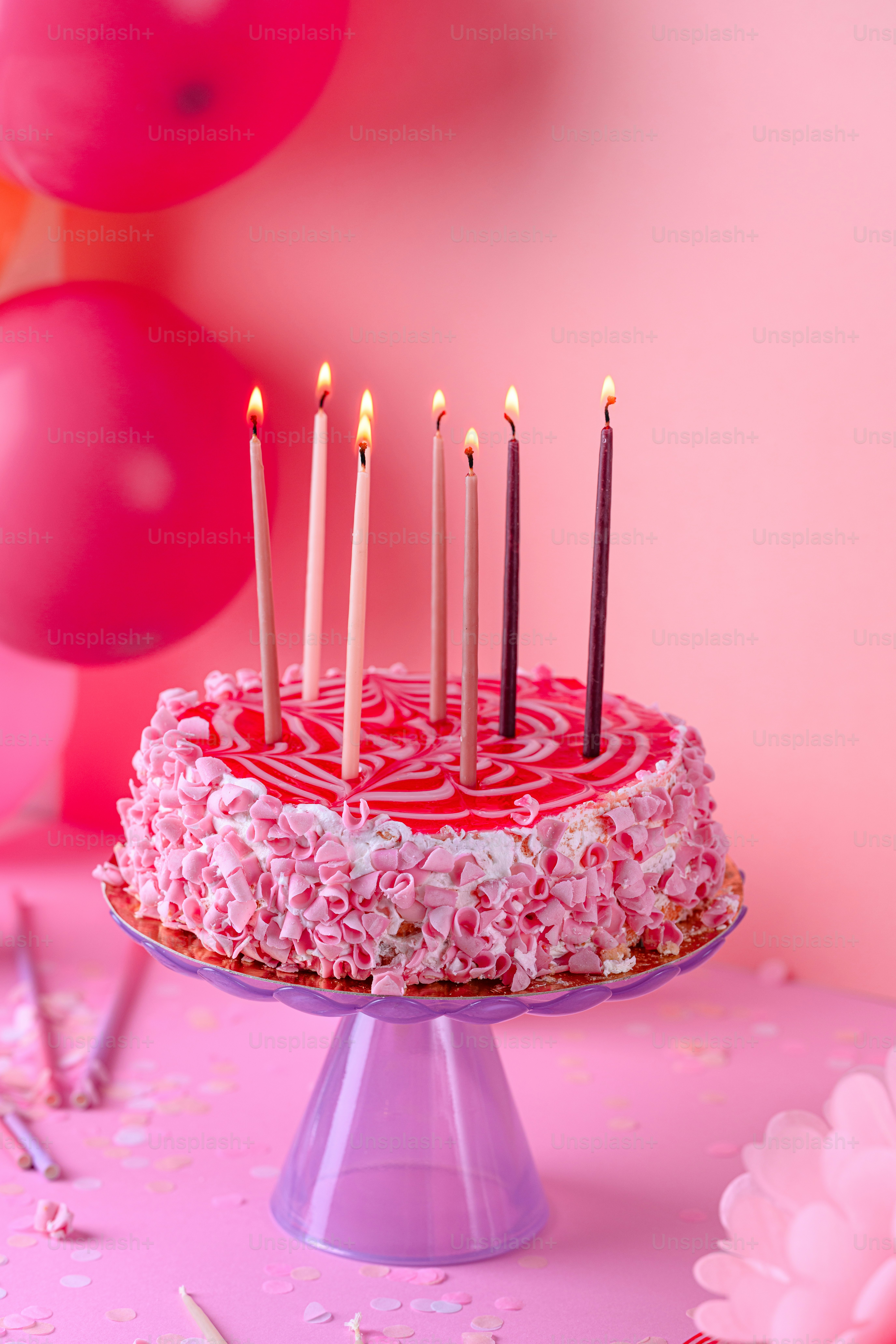 a birthday cake with pink frosting and lit candles