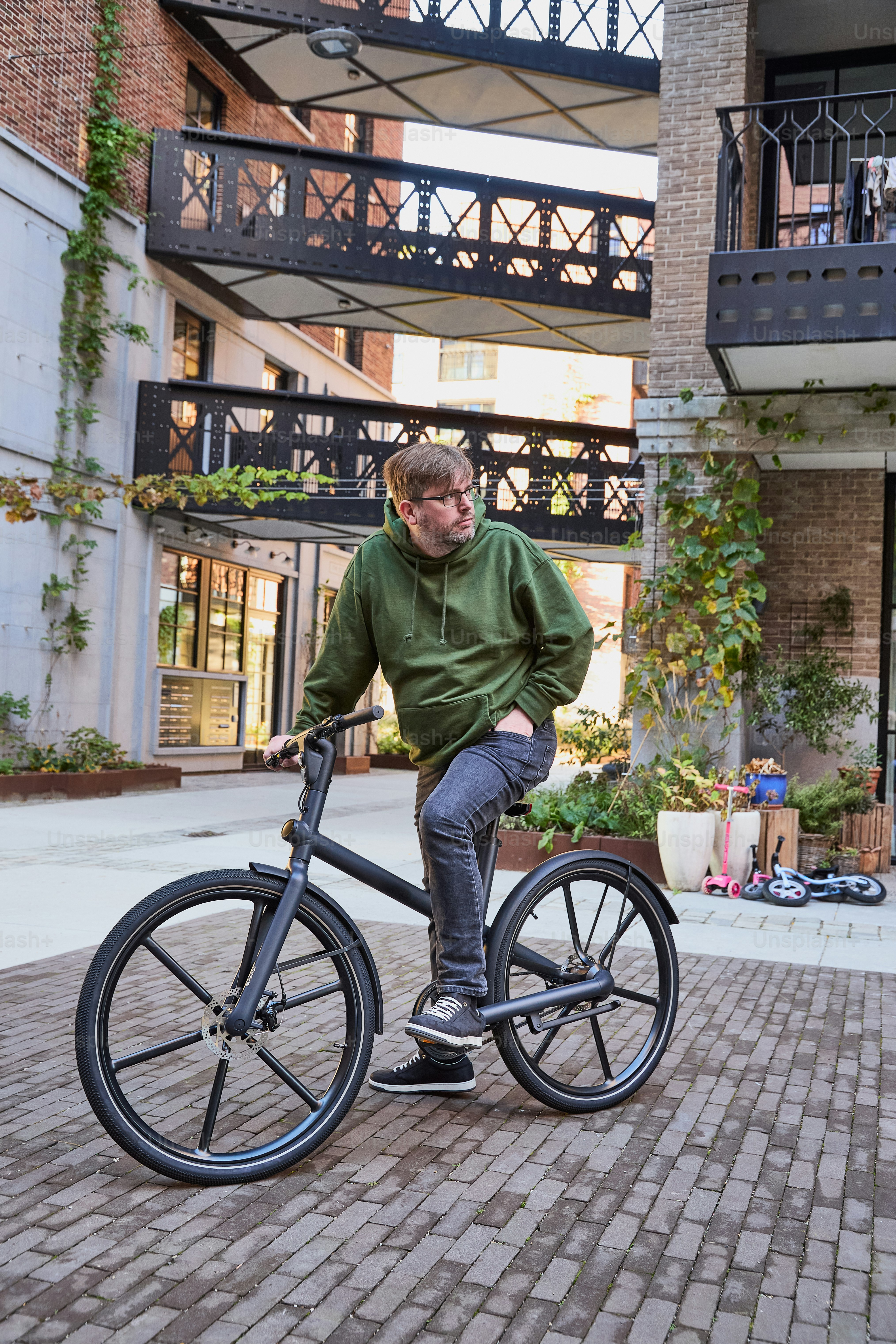 A man riding a bike down a brick road photo – Sustainability Image on ...