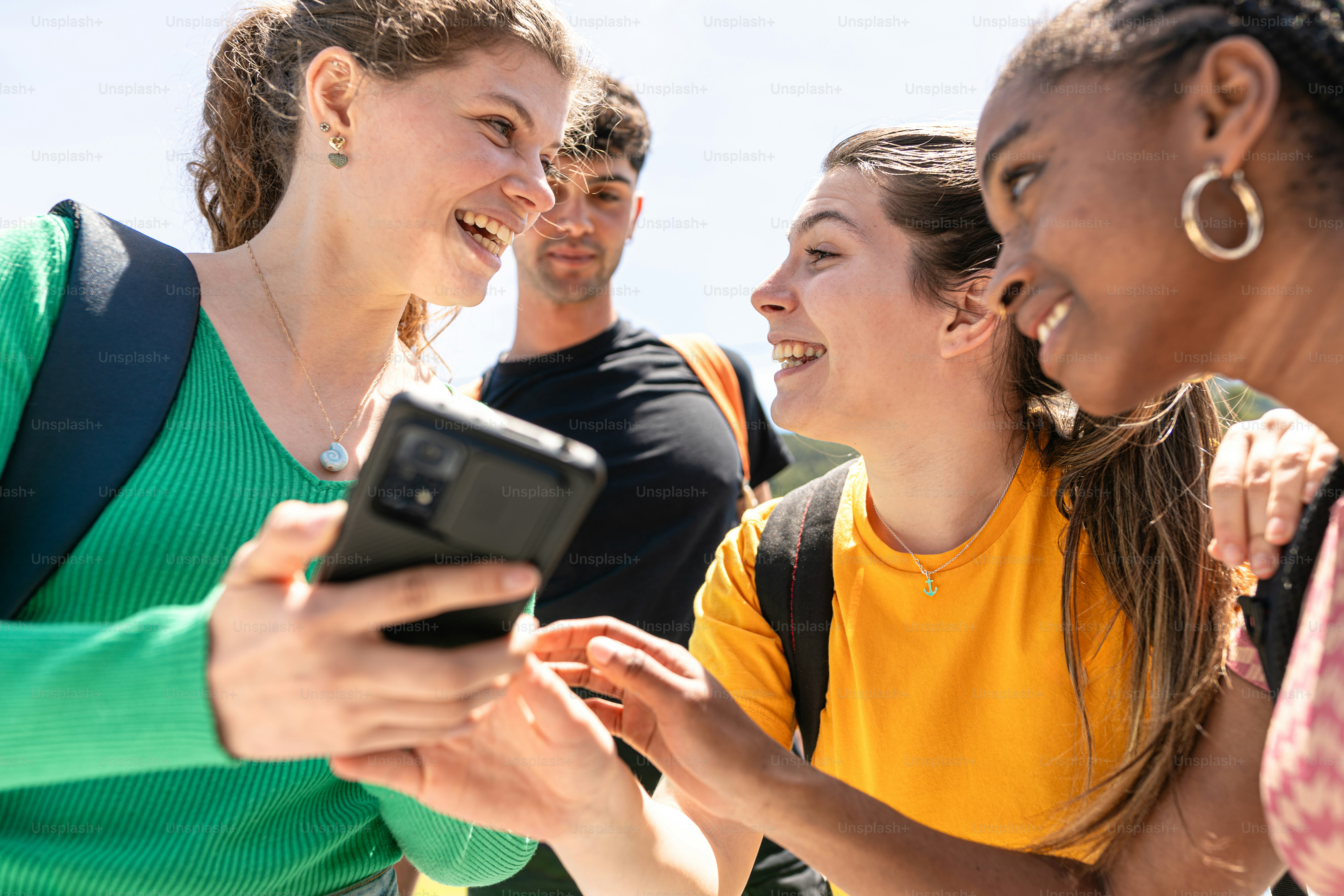 un gruppo di persone in piedi l'una intorno all'altra che guardano un telefono cellulare