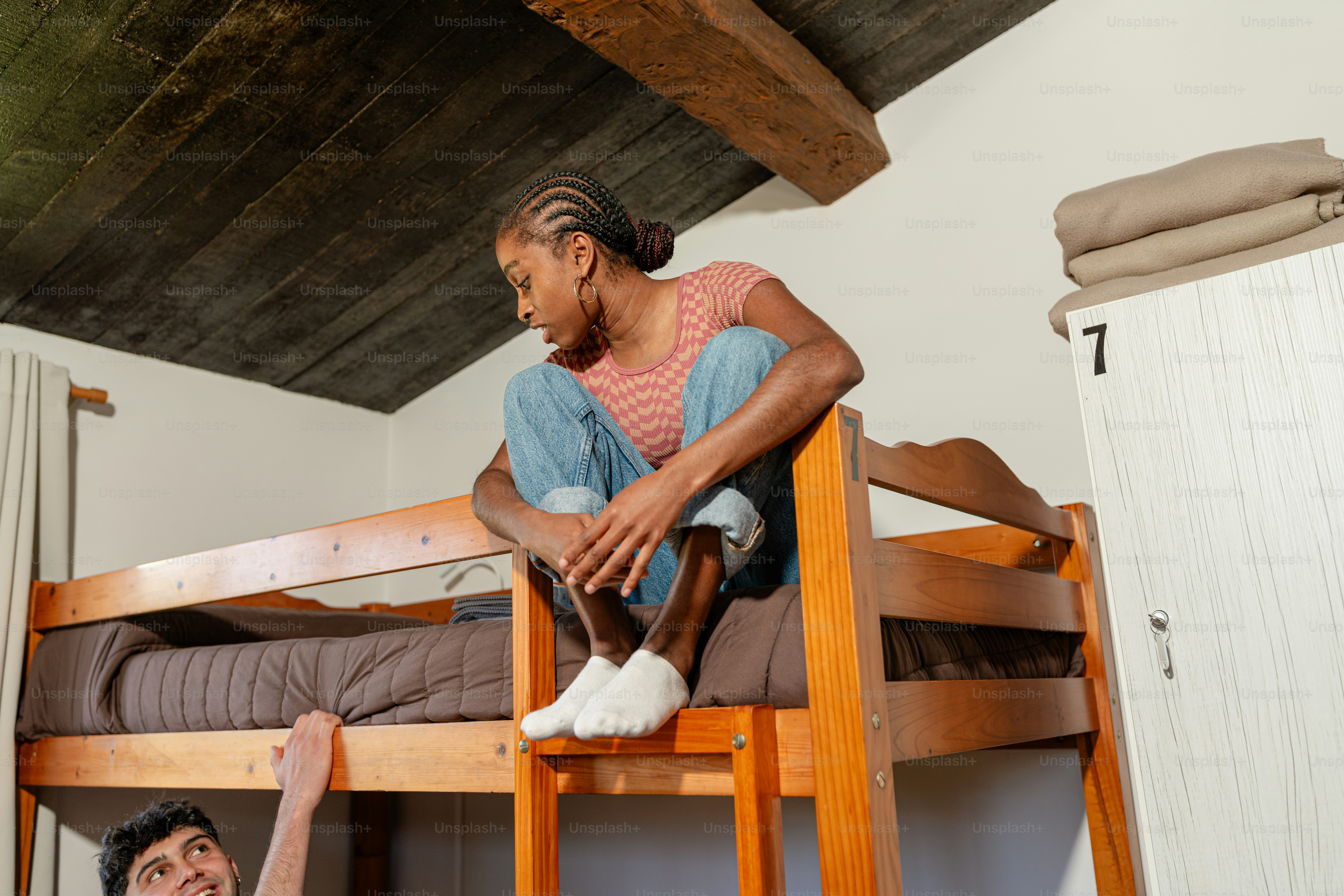 a woman sitting on top of a wooden bunk bed