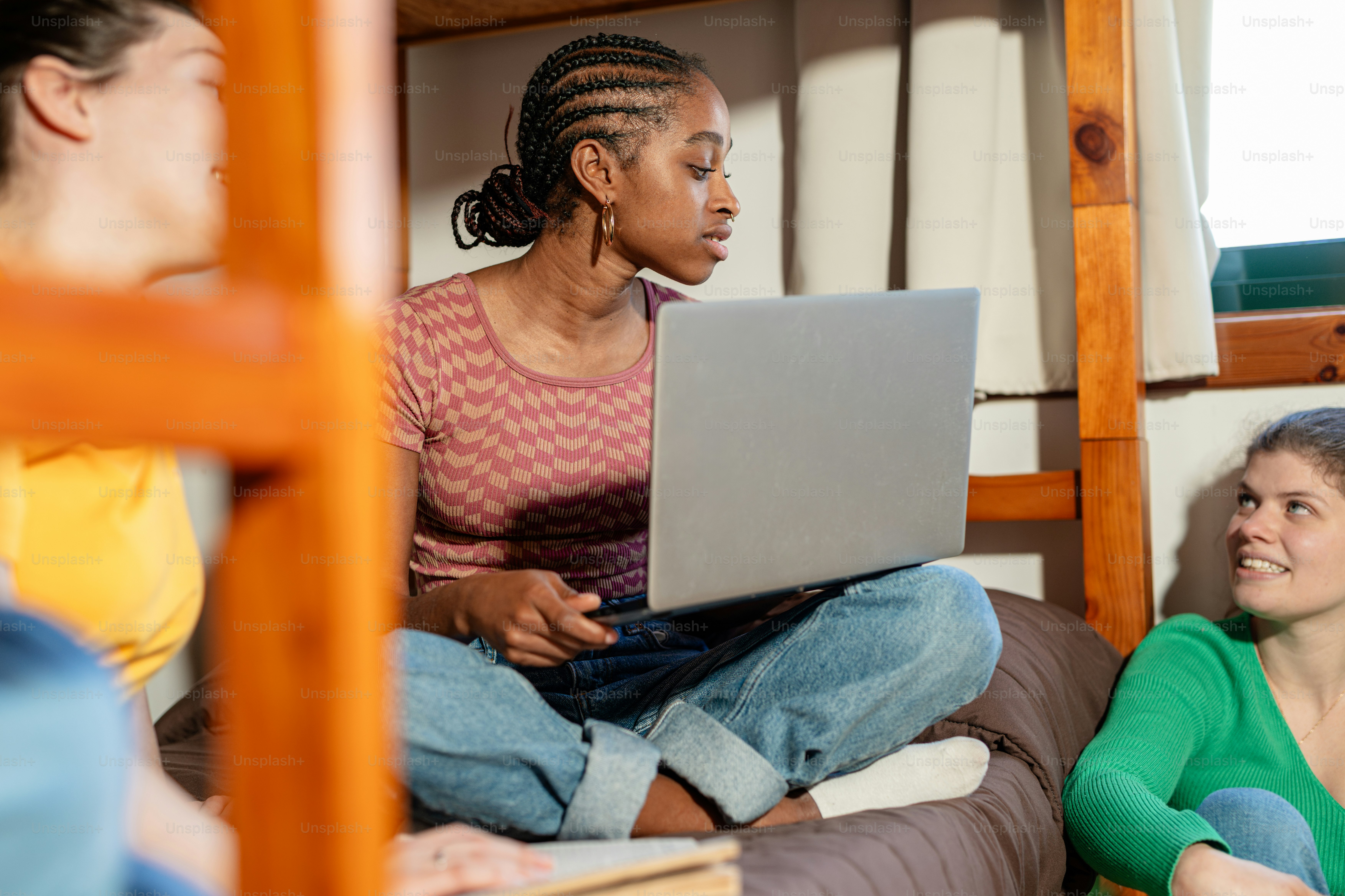 a woman sitting on a bed using a laptop computer