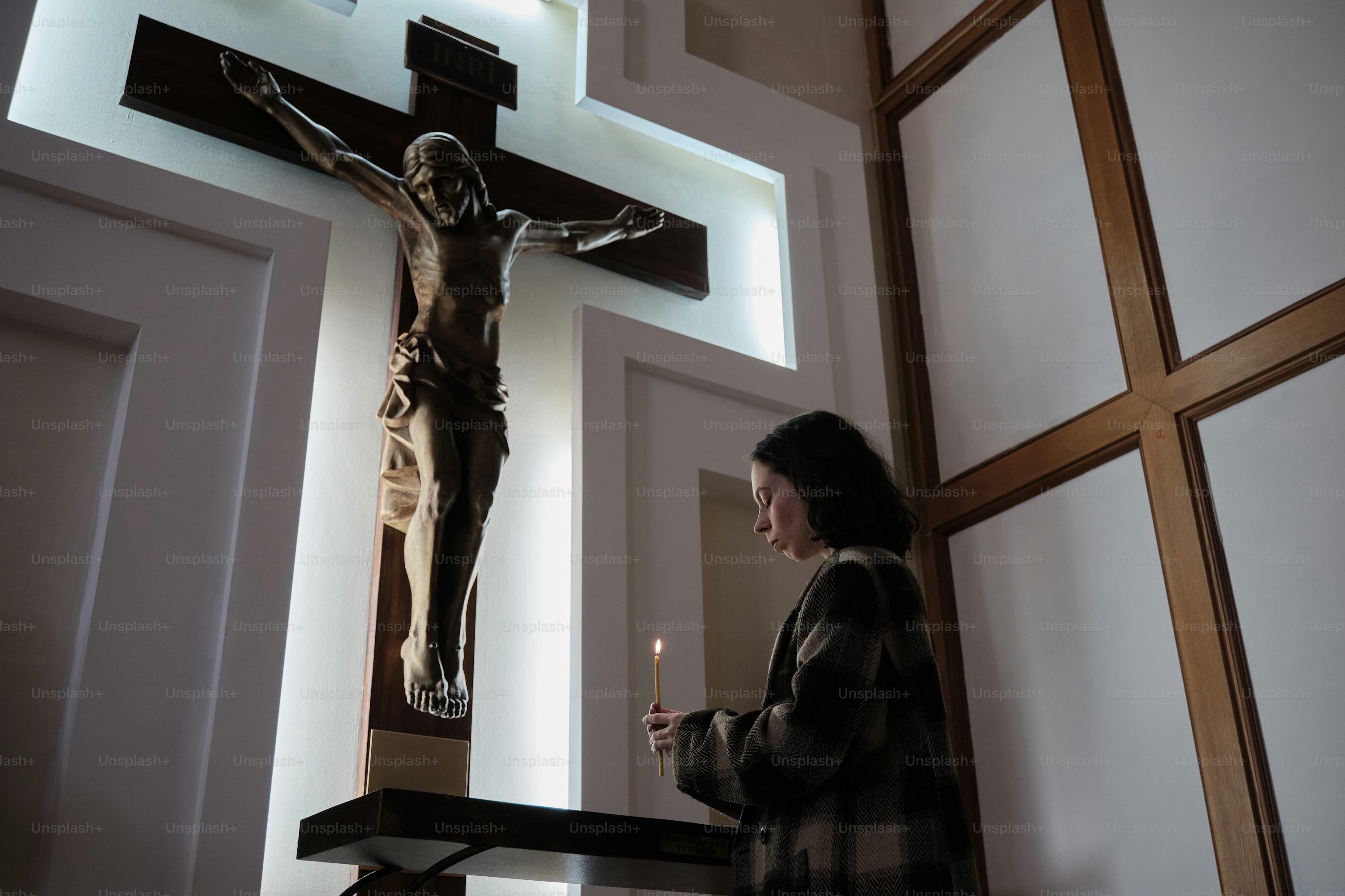 a woman standing in front of a crucifix
