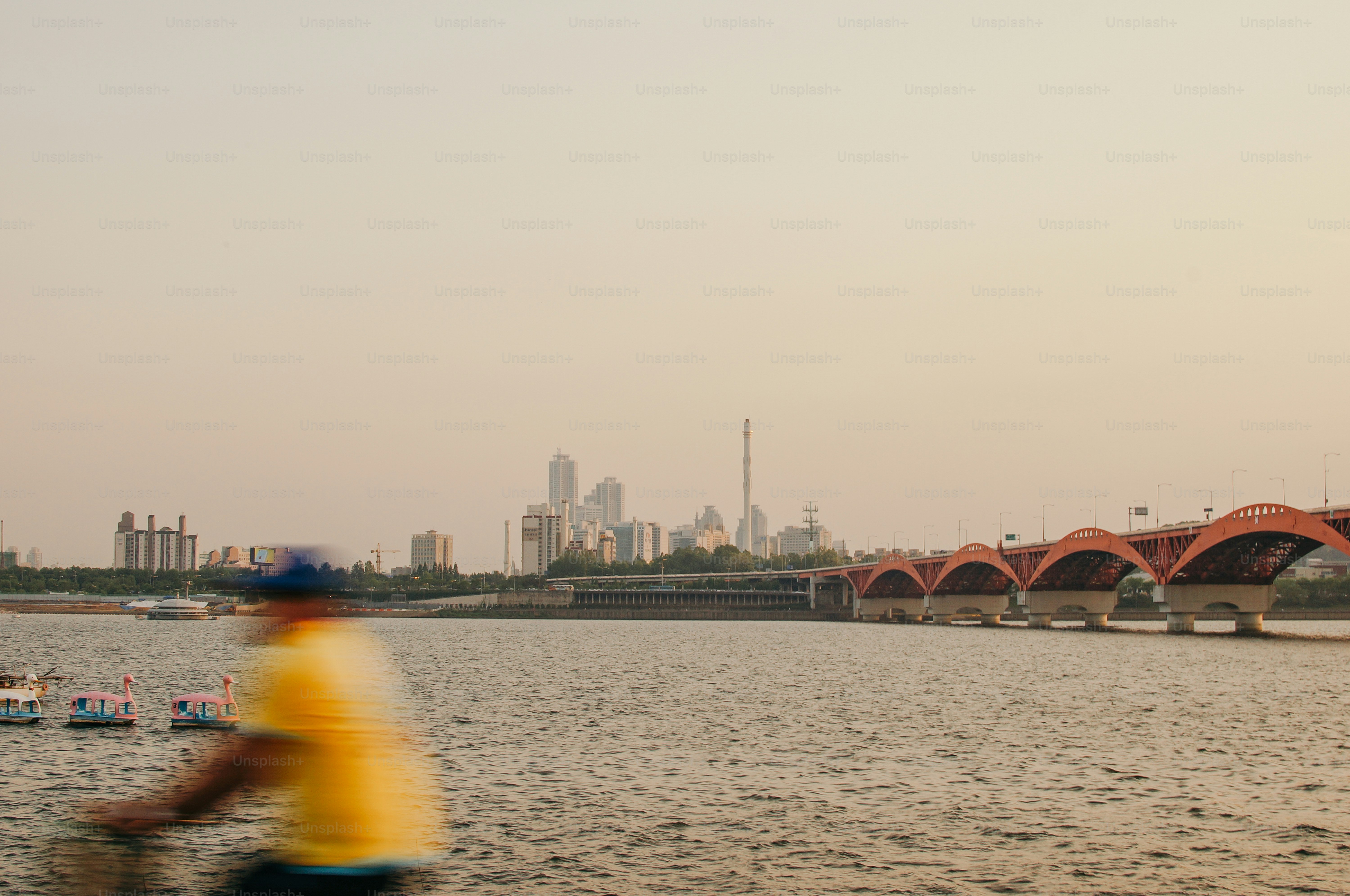 a person riding a bike on a river with a bridge in the background