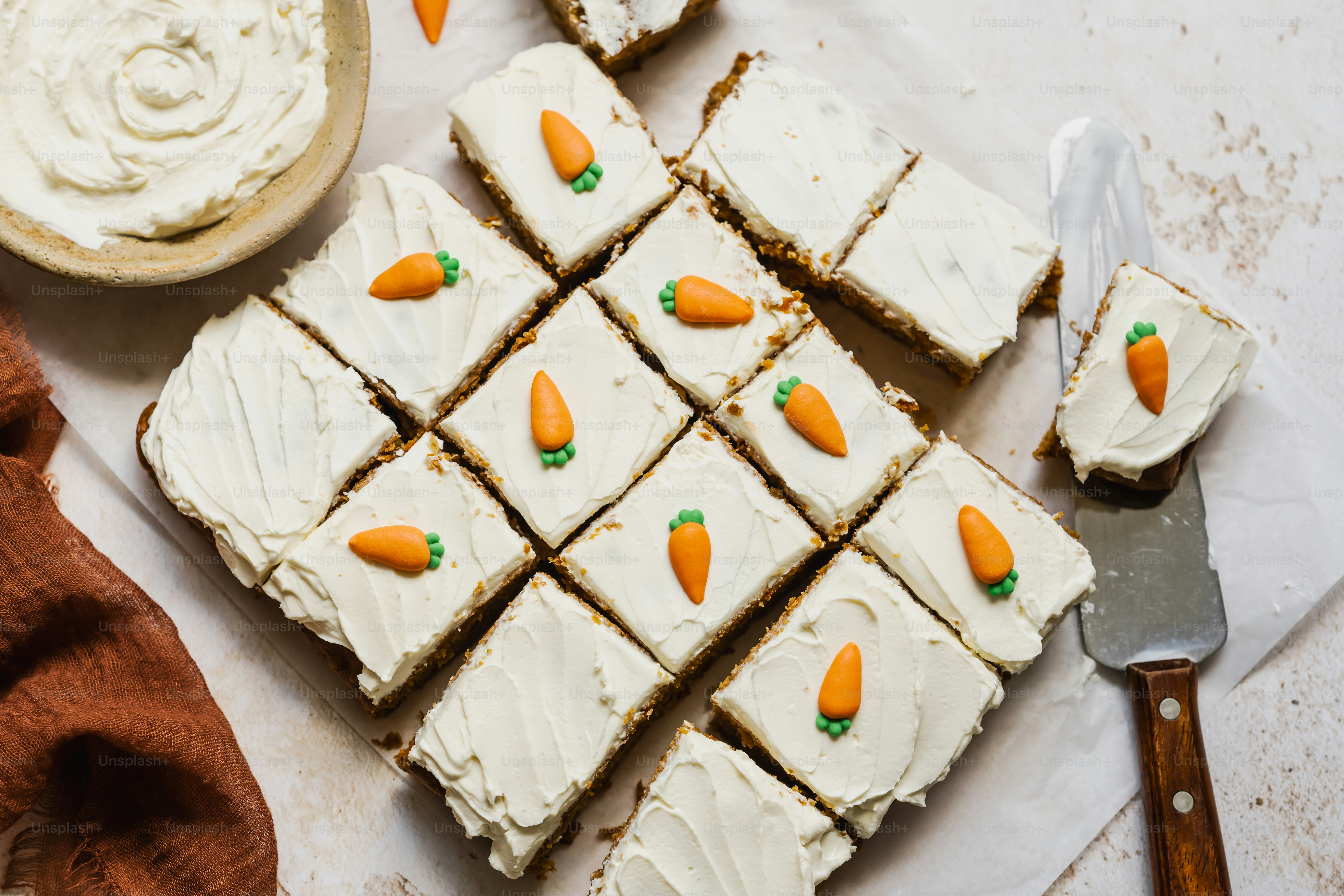a white plate topped with carrots next to a bowl of frosting