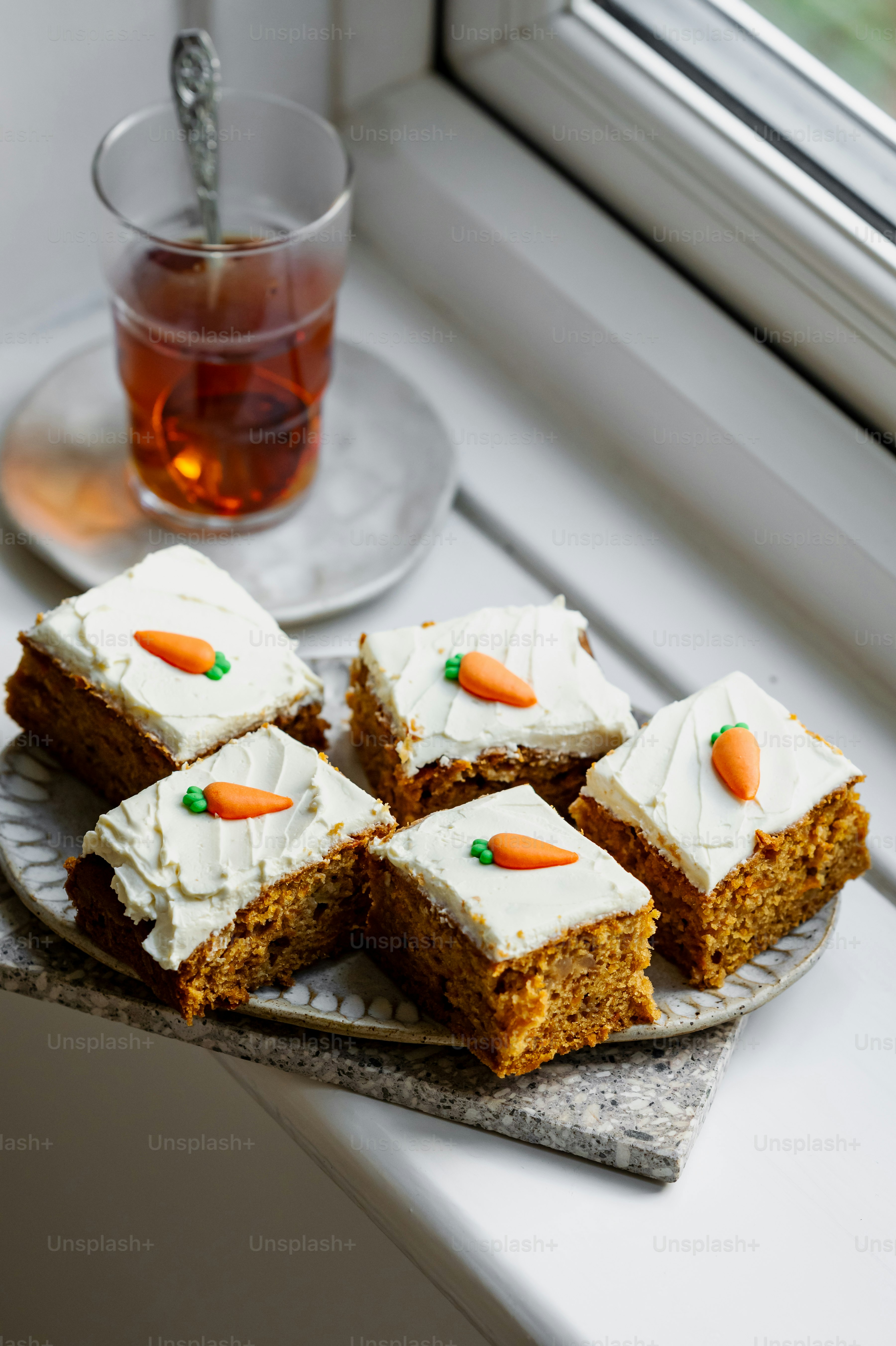 a plate of carrot cake next to a cup of tea