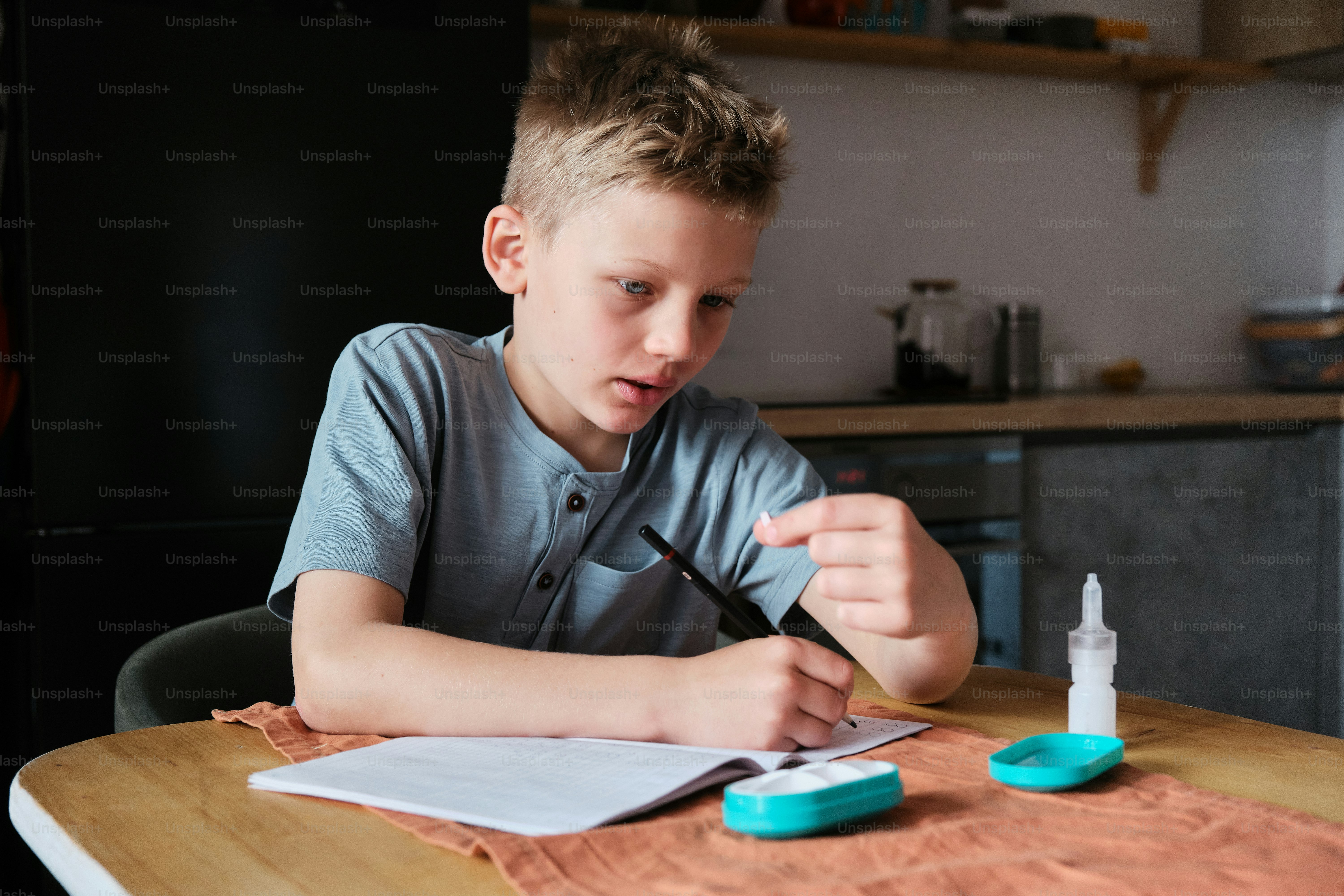 a young boy sitting at a table writing on a piece of paper
