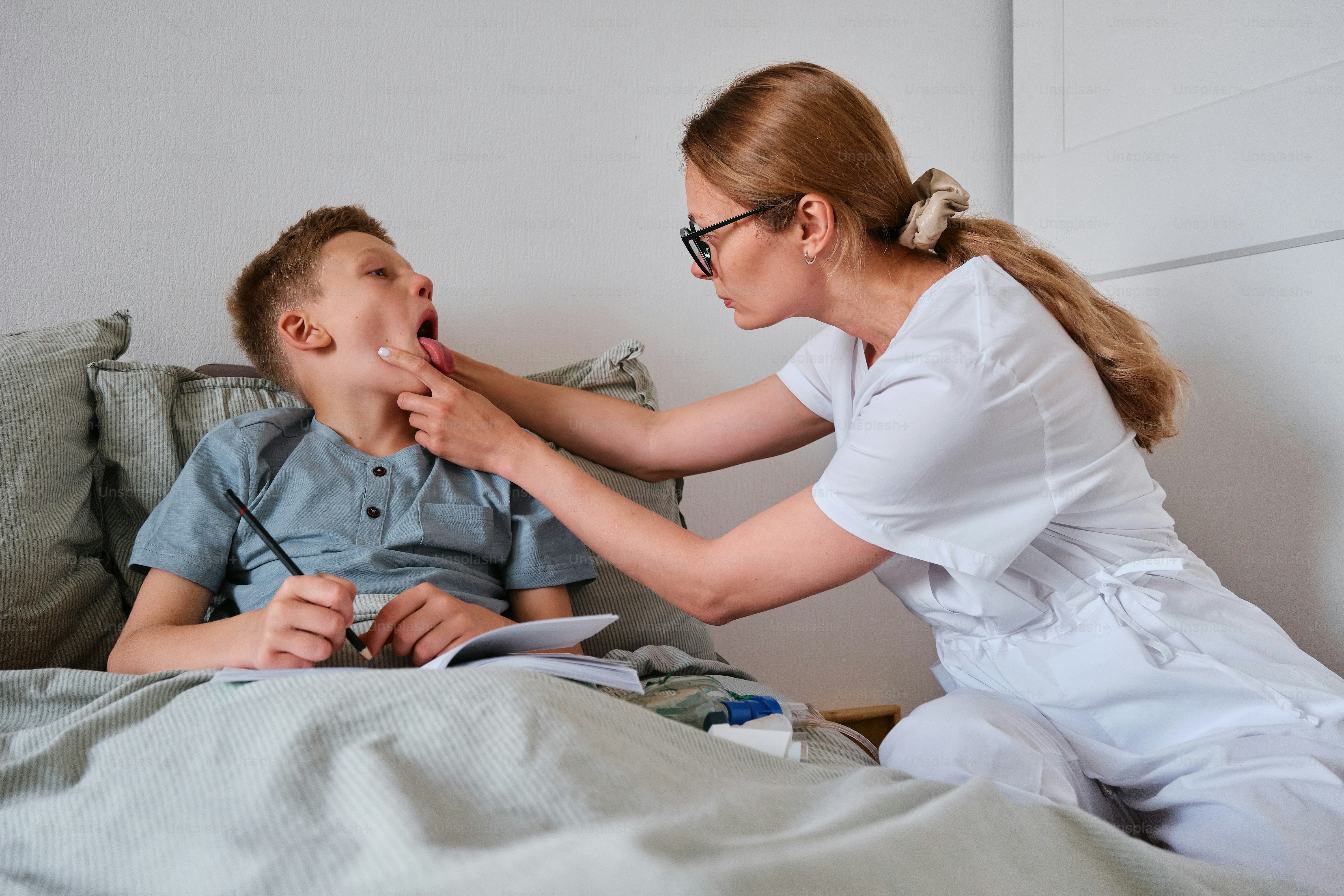 a woman helping a young boy to brush his teeth