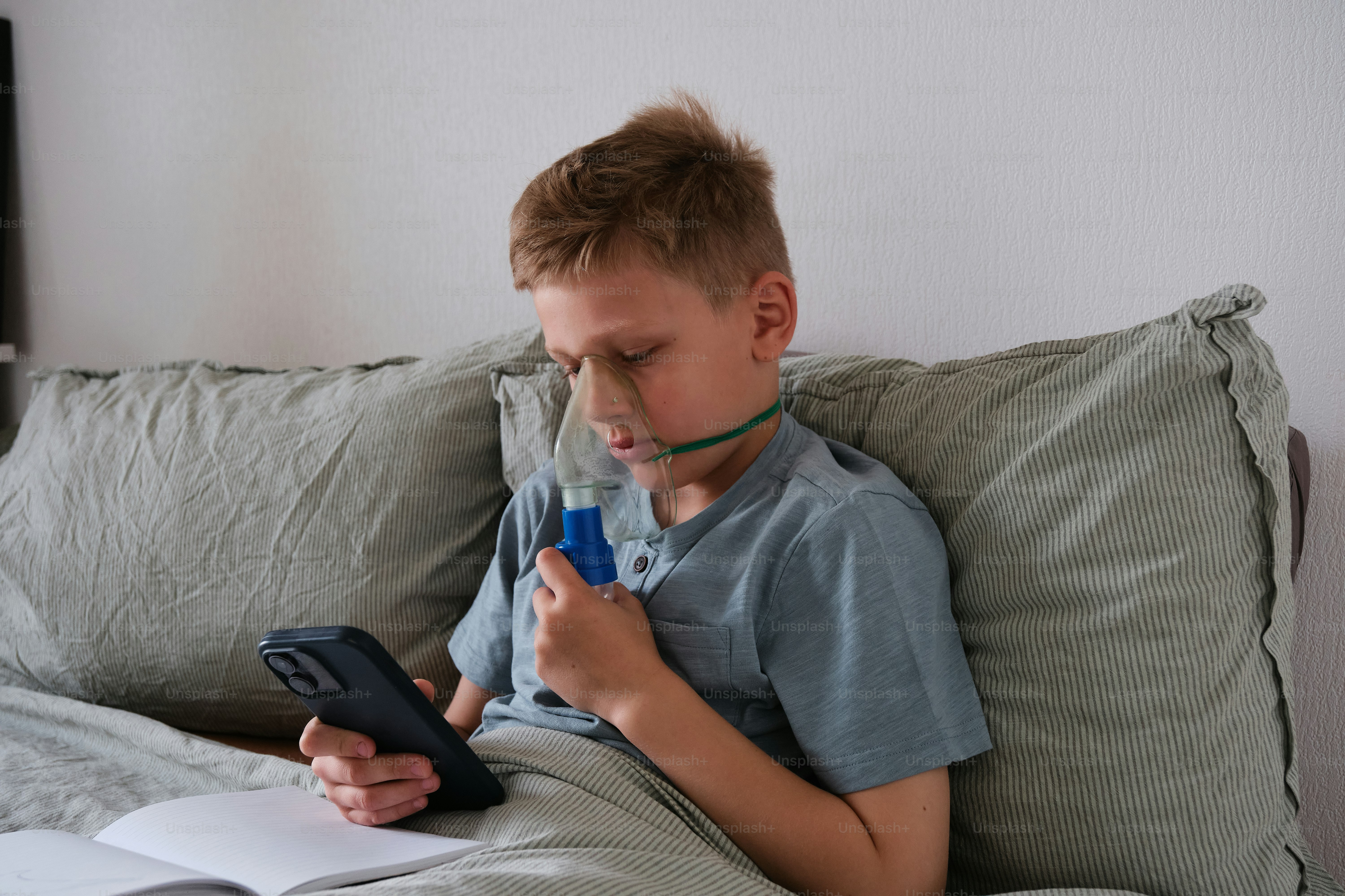 a young boy sitting on a bed holding a remote control