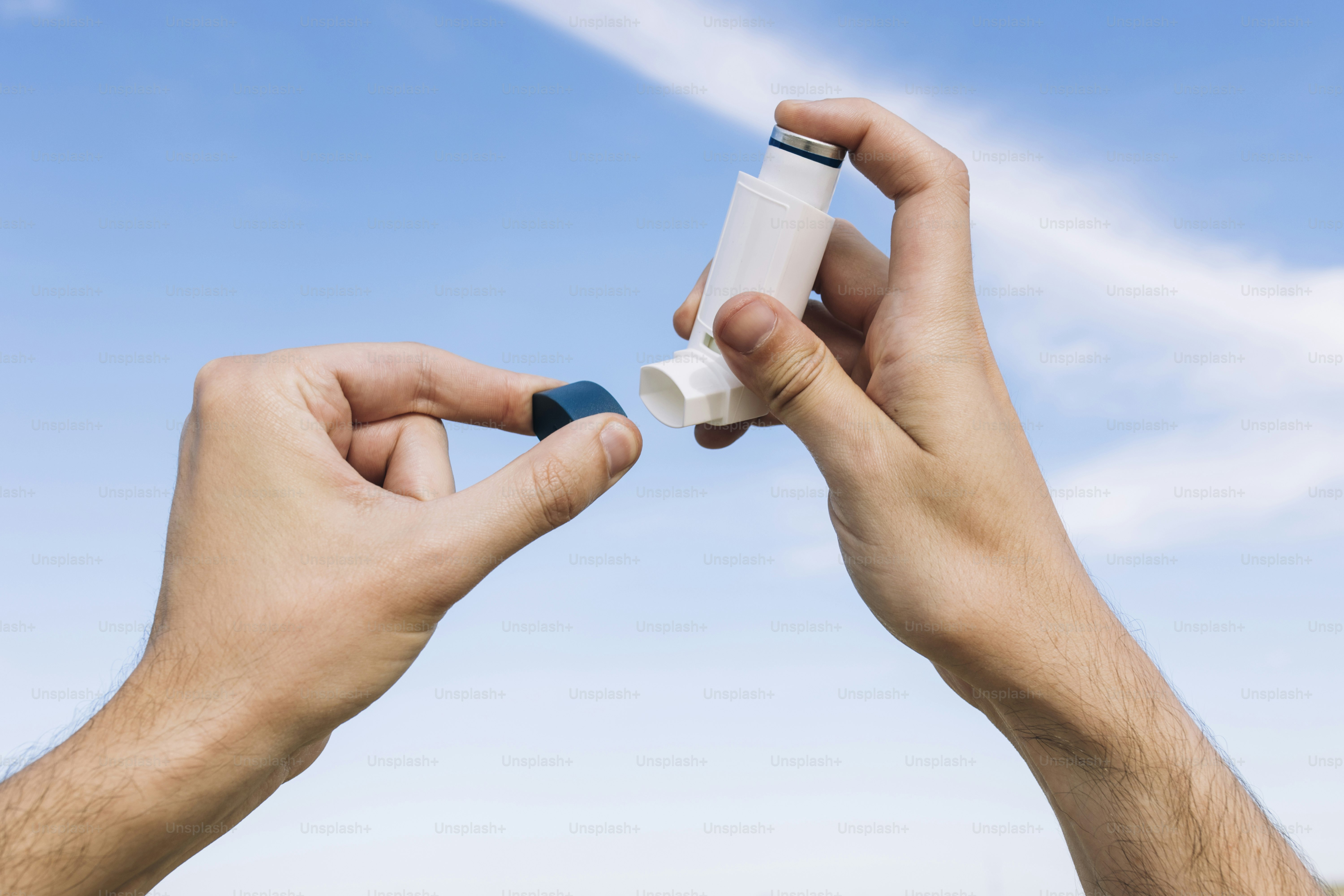 deux mains tenant un petit tube de médicament contre un ciel bleu