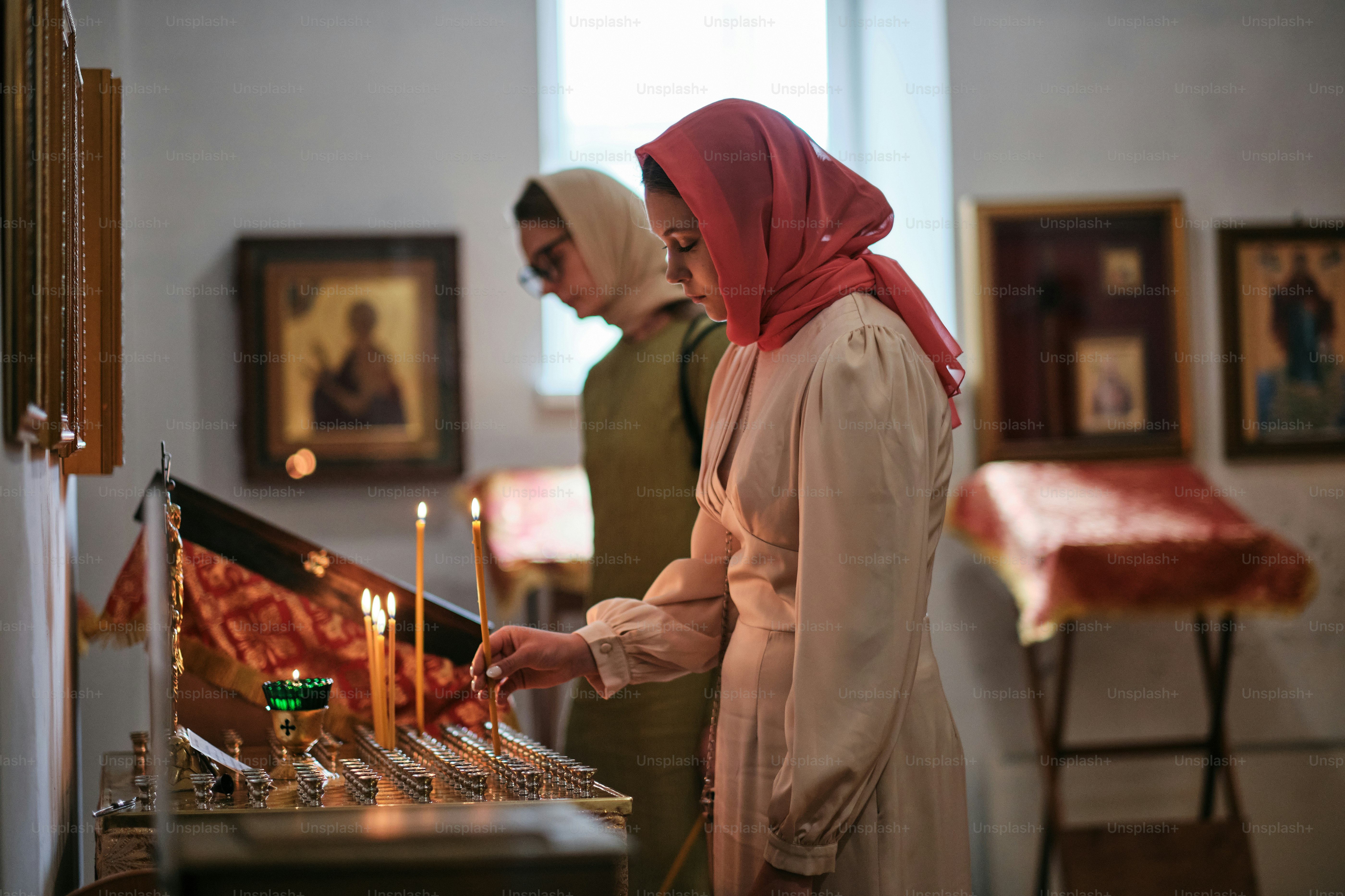 Uma mulher em um hijab acende velas em uma igreja