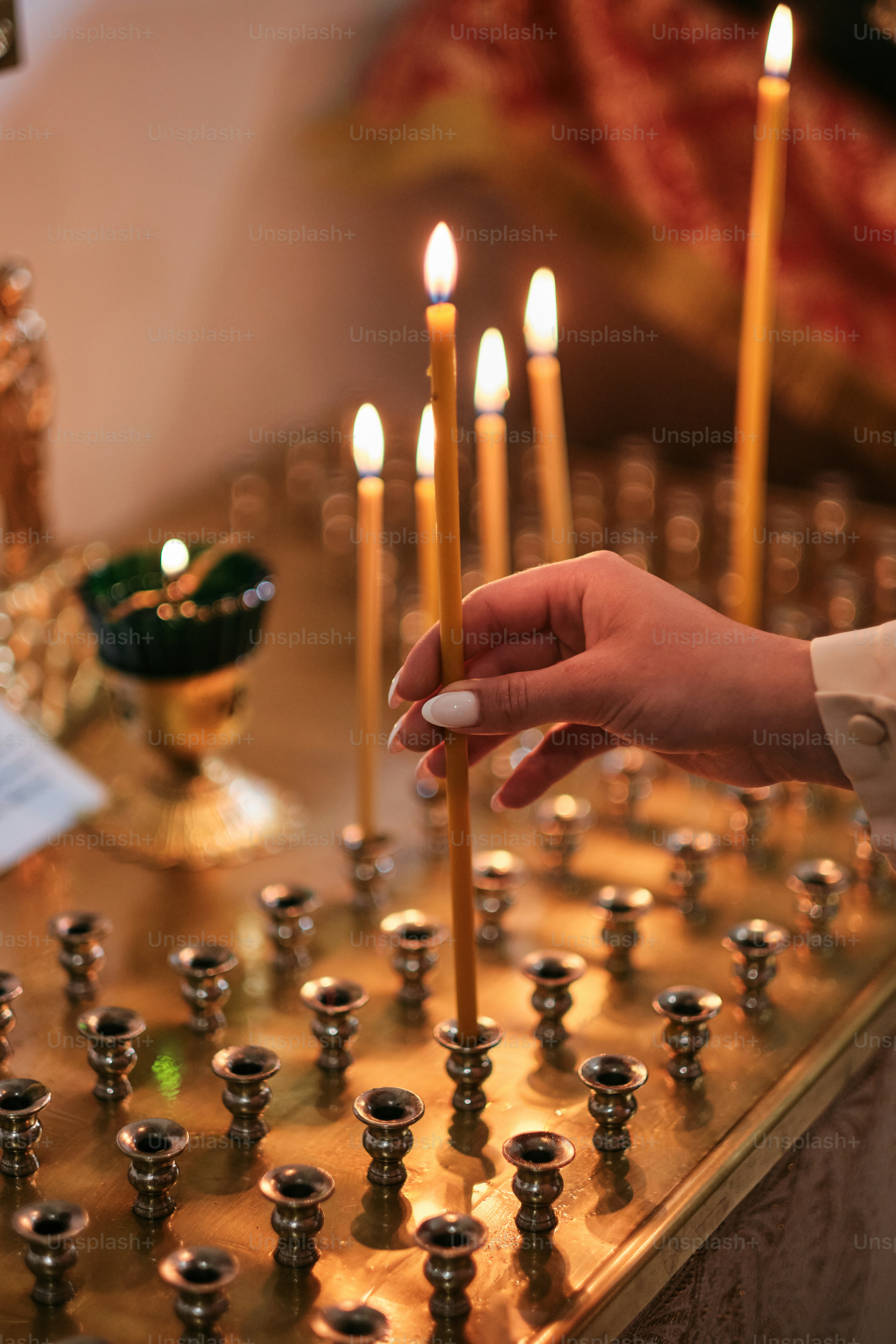 a person holding a lit candle in front of a number of candles