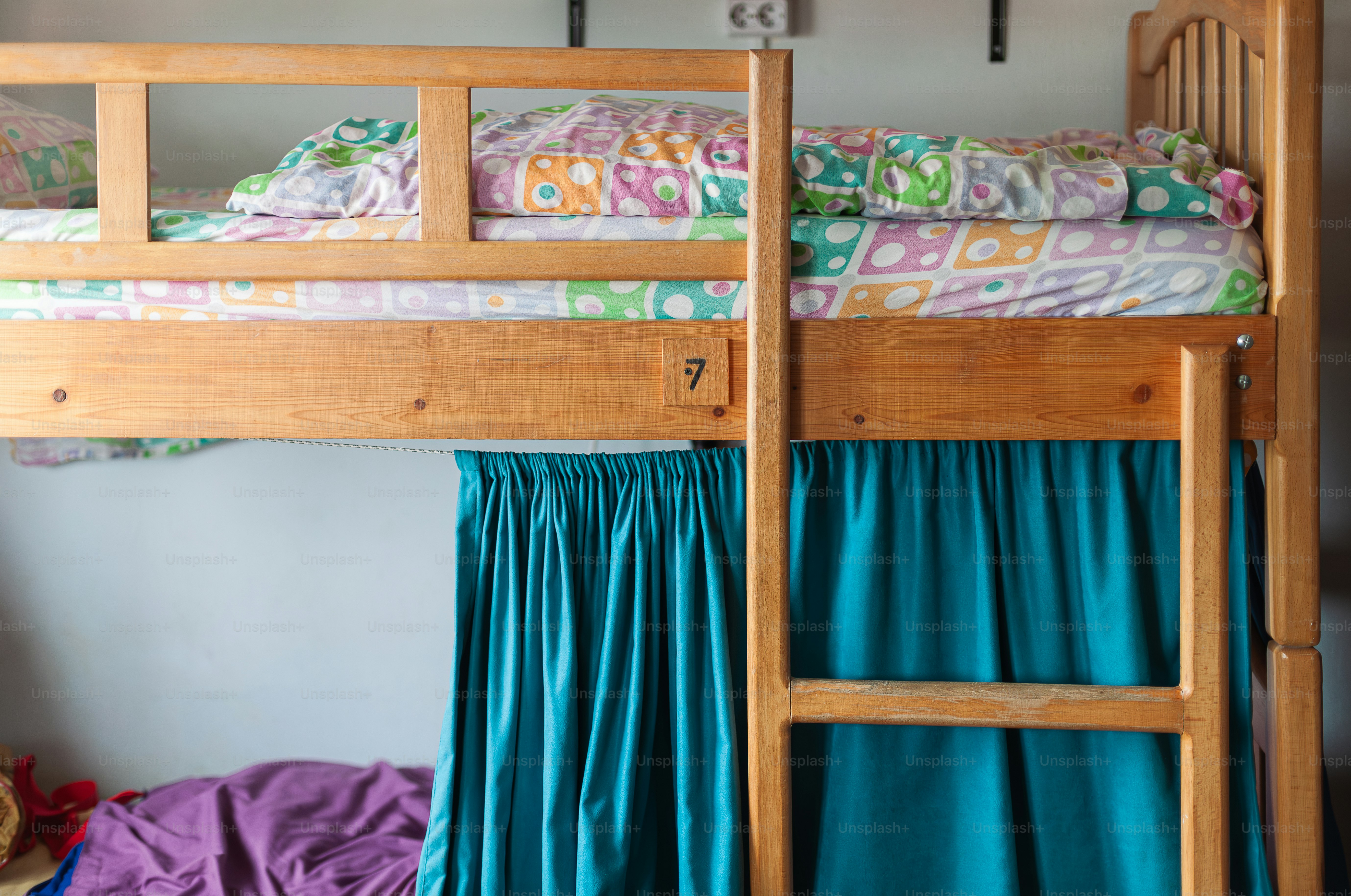 a wooden bunk bed with a blue curtain