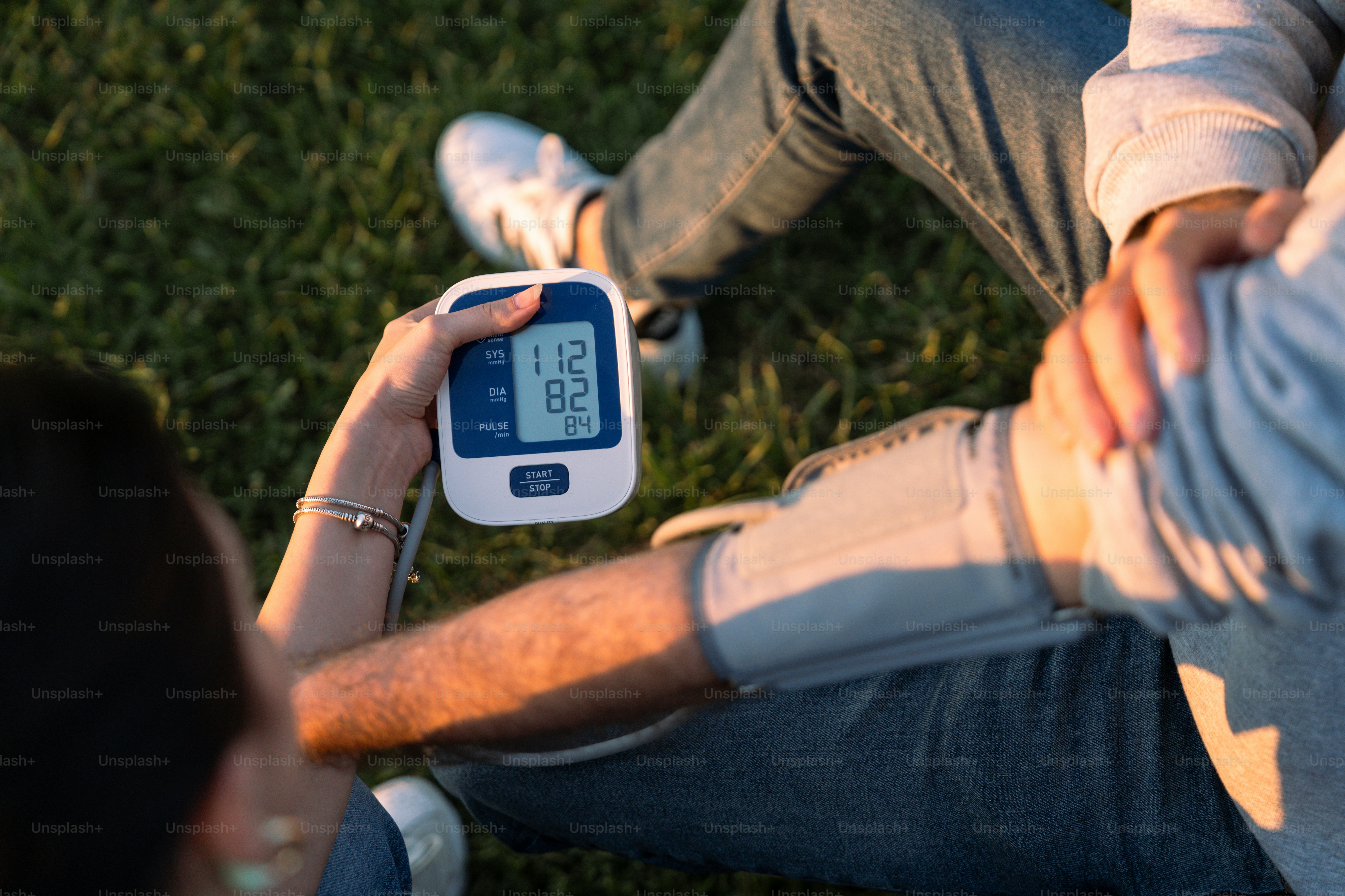 a person sitting on the grass holding a digital clock