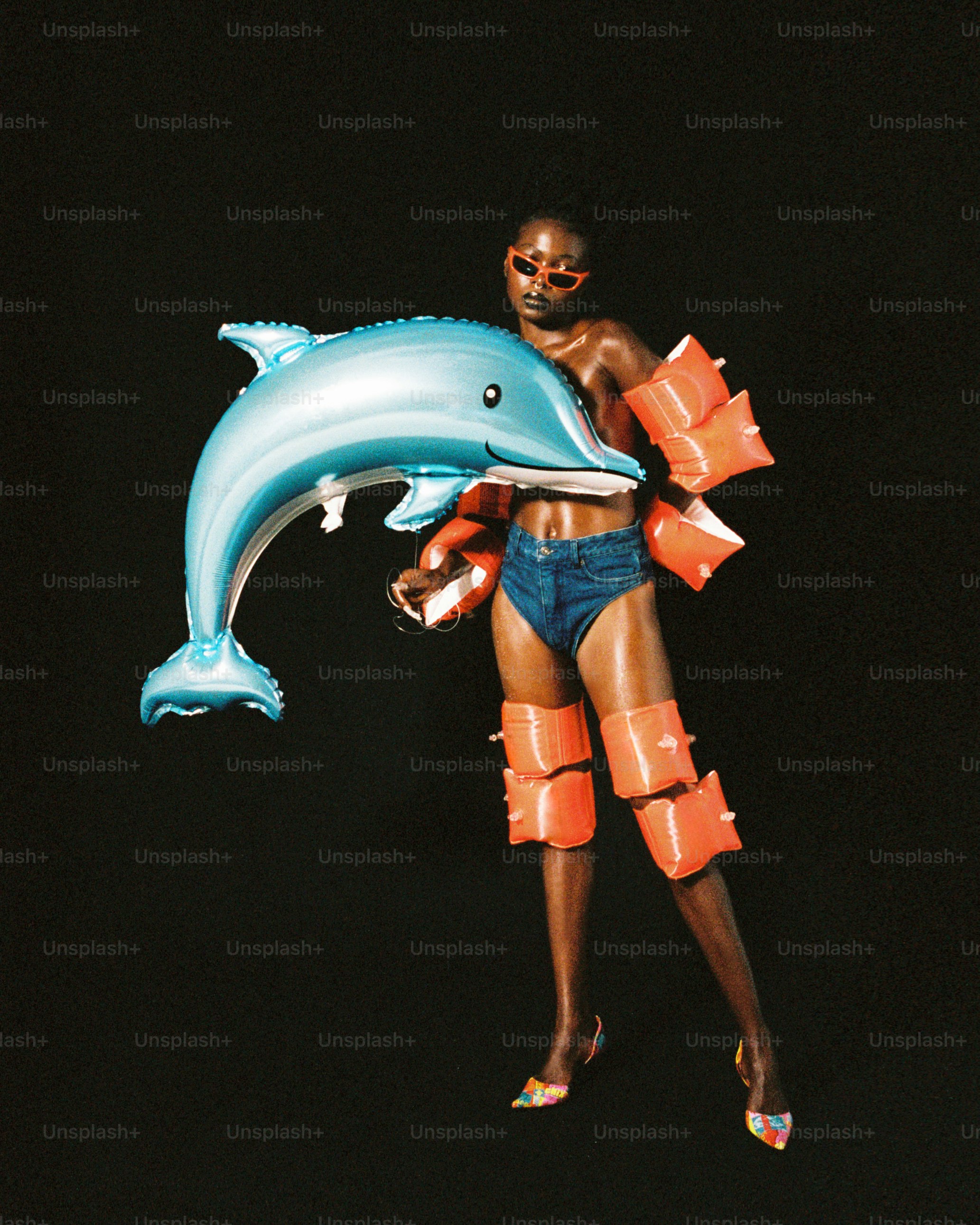 수영복을 입은 여성이 돌고래 풍선을 들고 있다