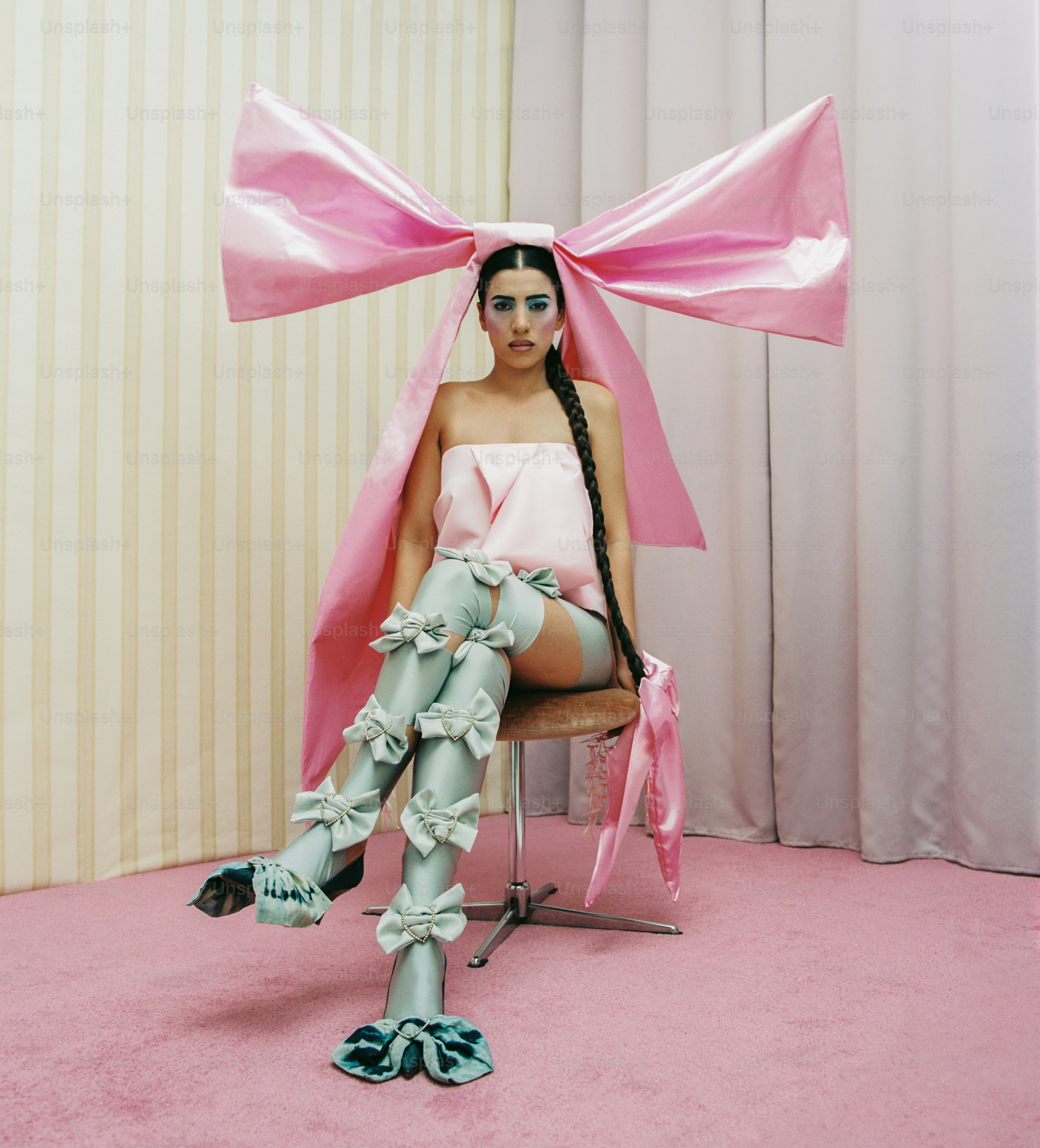 a woman sitting in a chair with a pink bow on her head