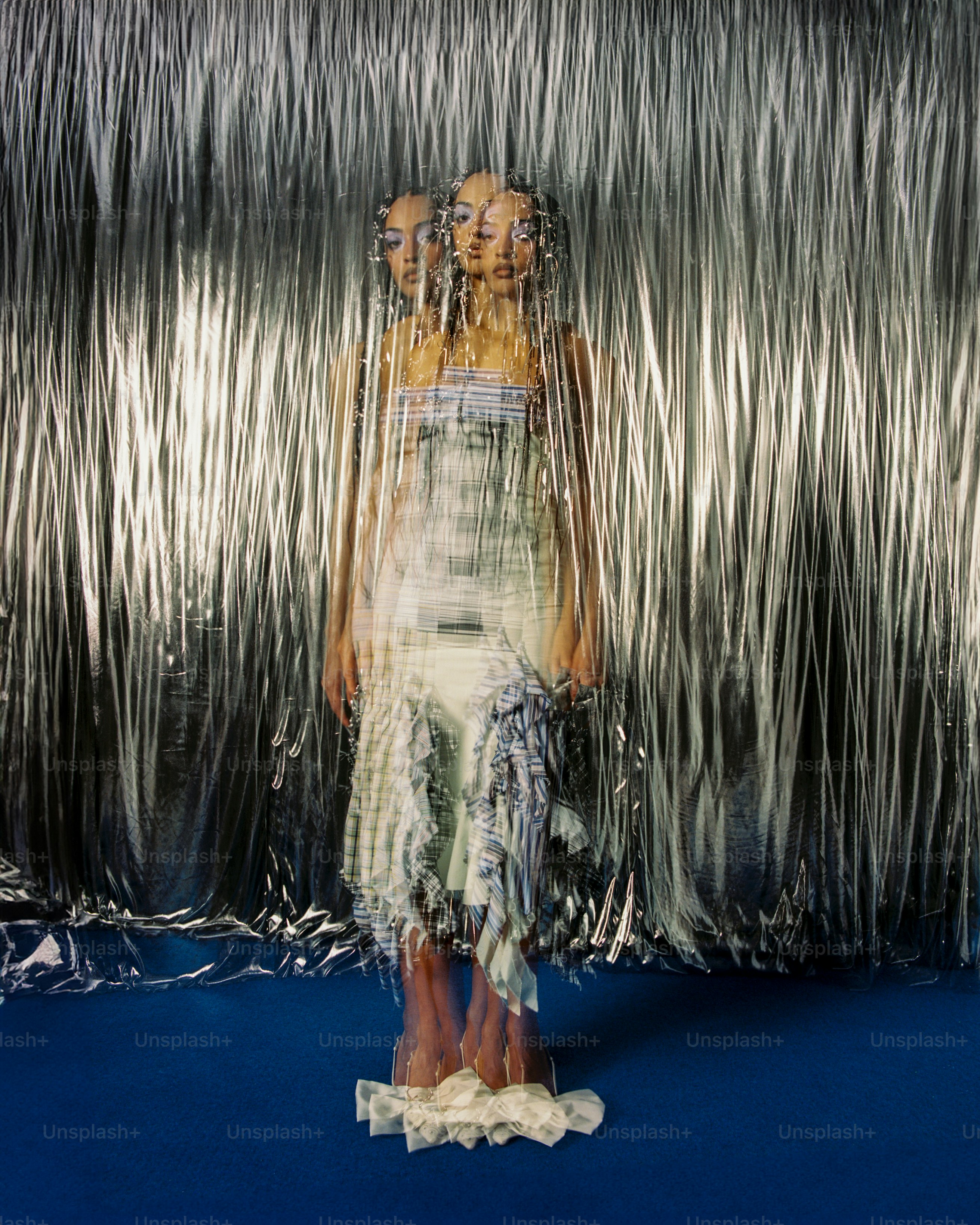 a woman standing in front of a silver curtain