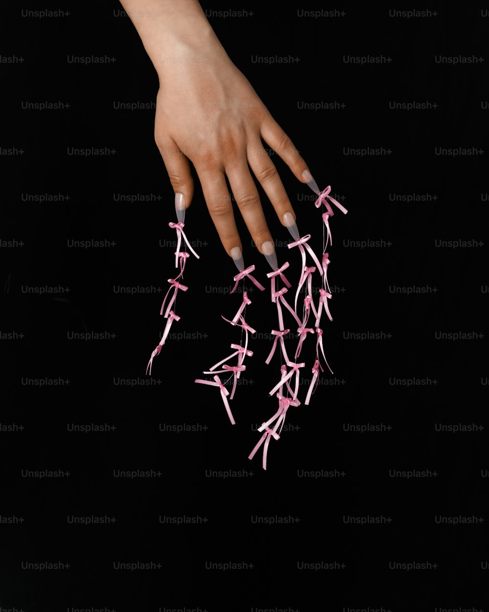 la mano de una mujer sosteniendo una ristra de palos rosas
