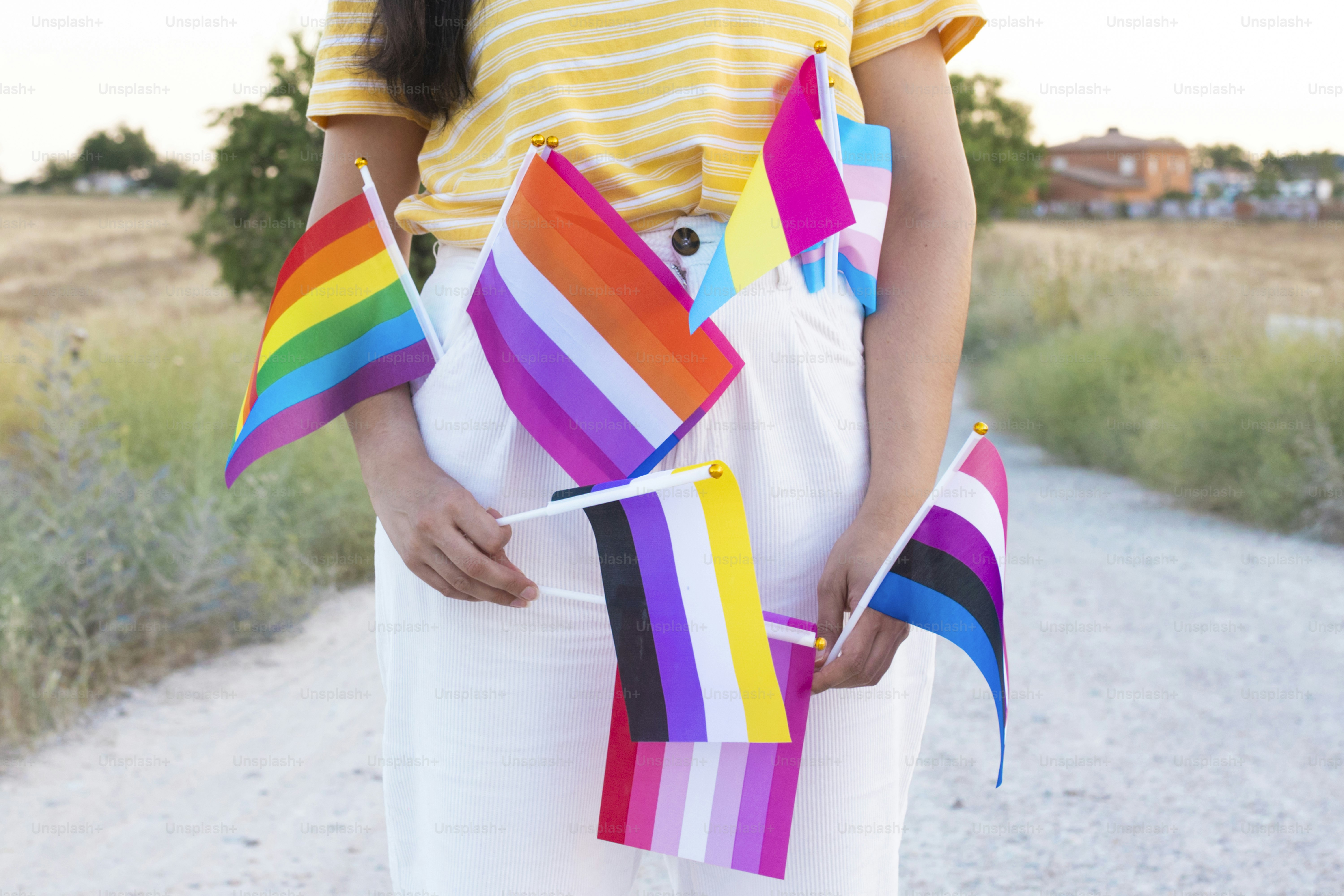 una mujer con una camisa a rayas amarillas sosteniendo una cometa arcoíris