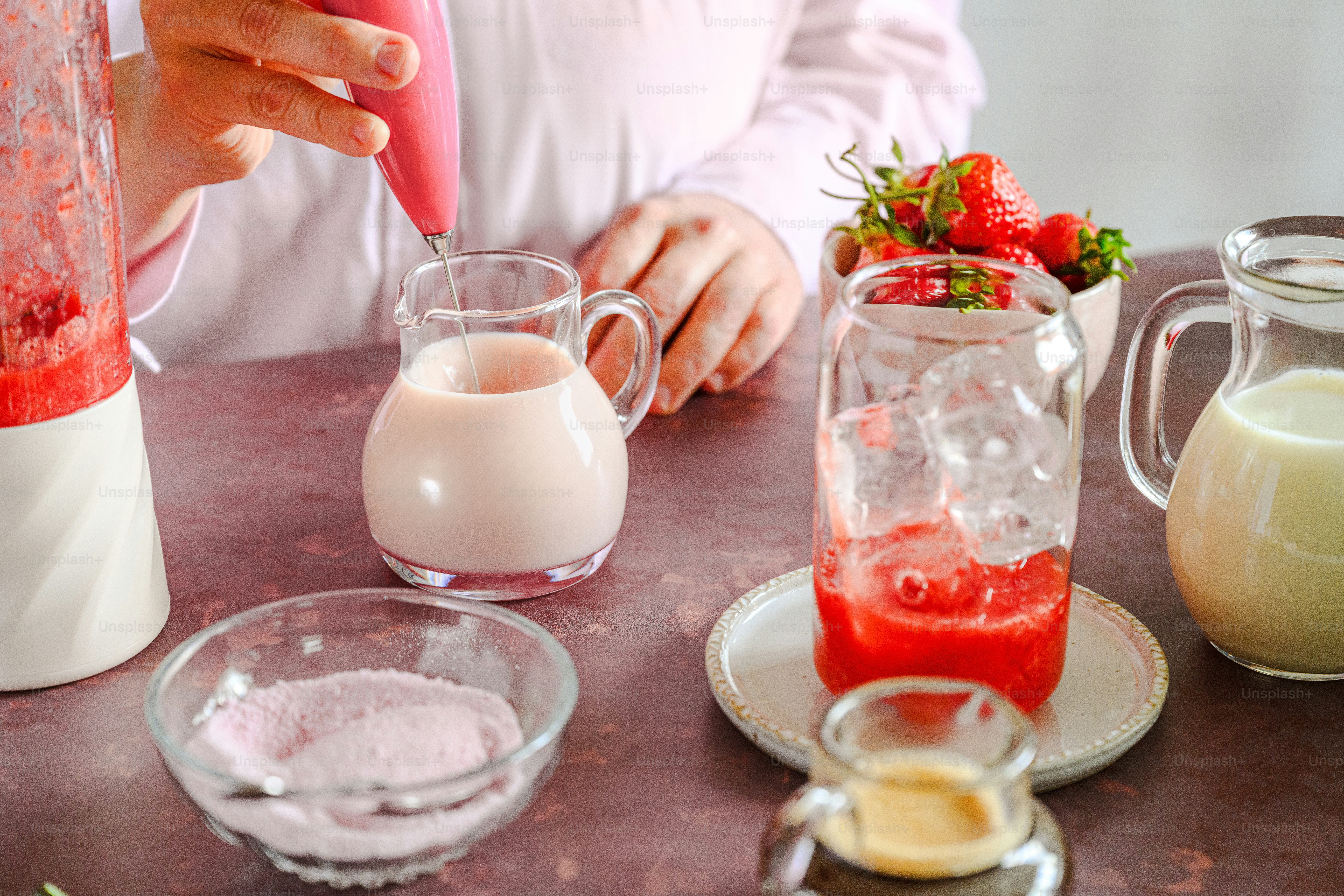 A woman is making a smoothie in a blender