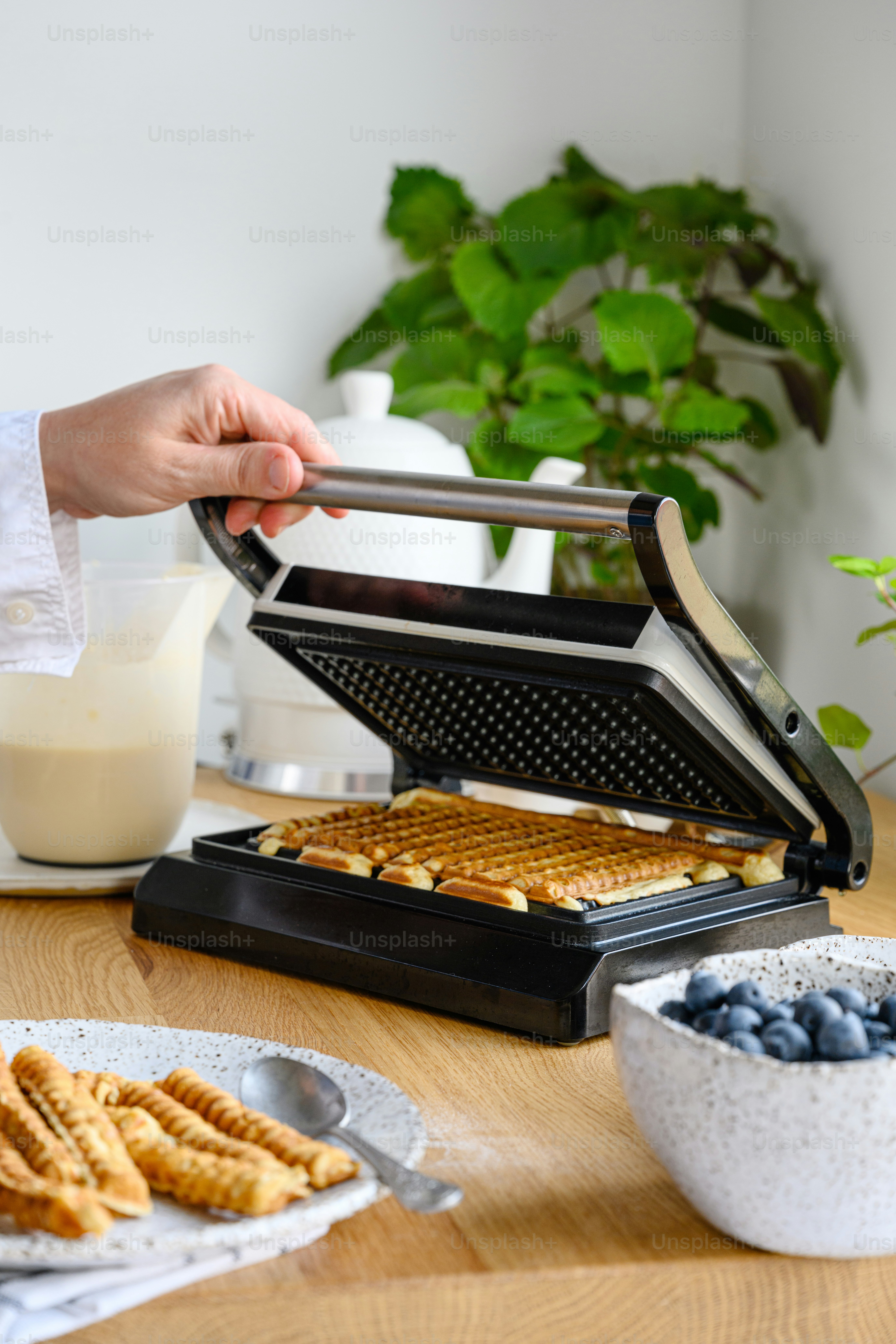 a person holding a waffle iron over a pan of waffles