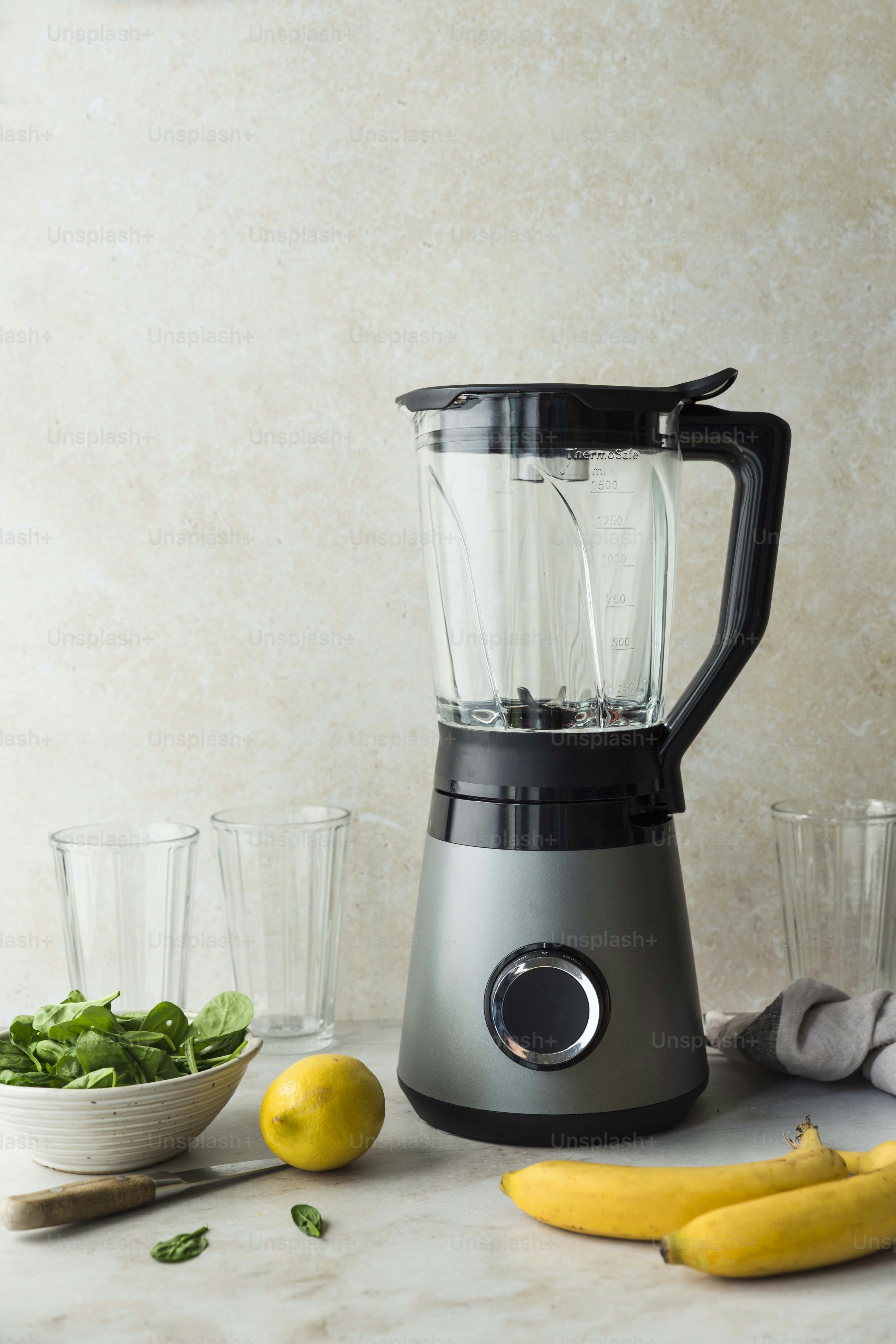 un frullatore seduto sopra un bancone accanto a una ciotola di frutta e