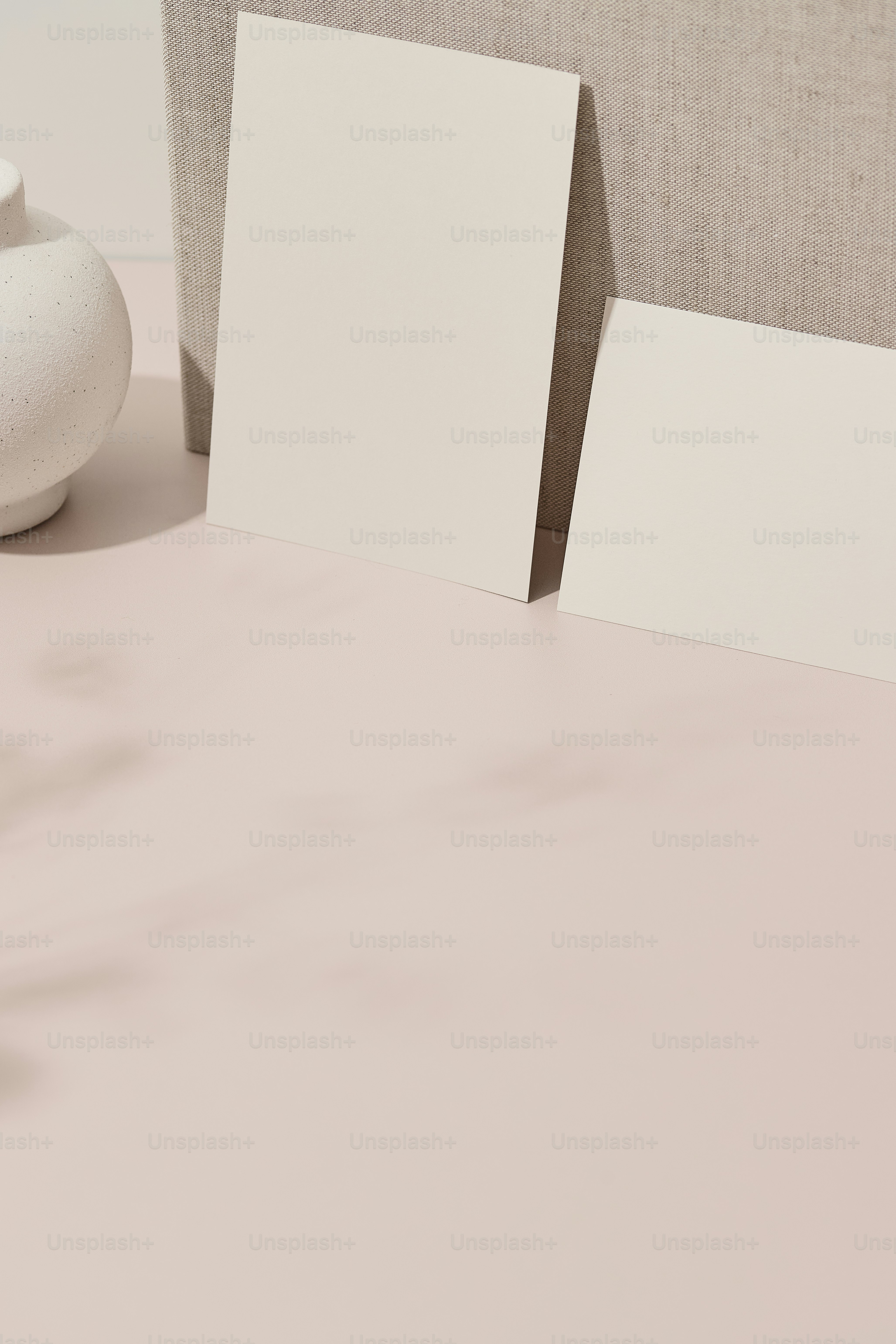 a table topped with two blank cards next to a vase