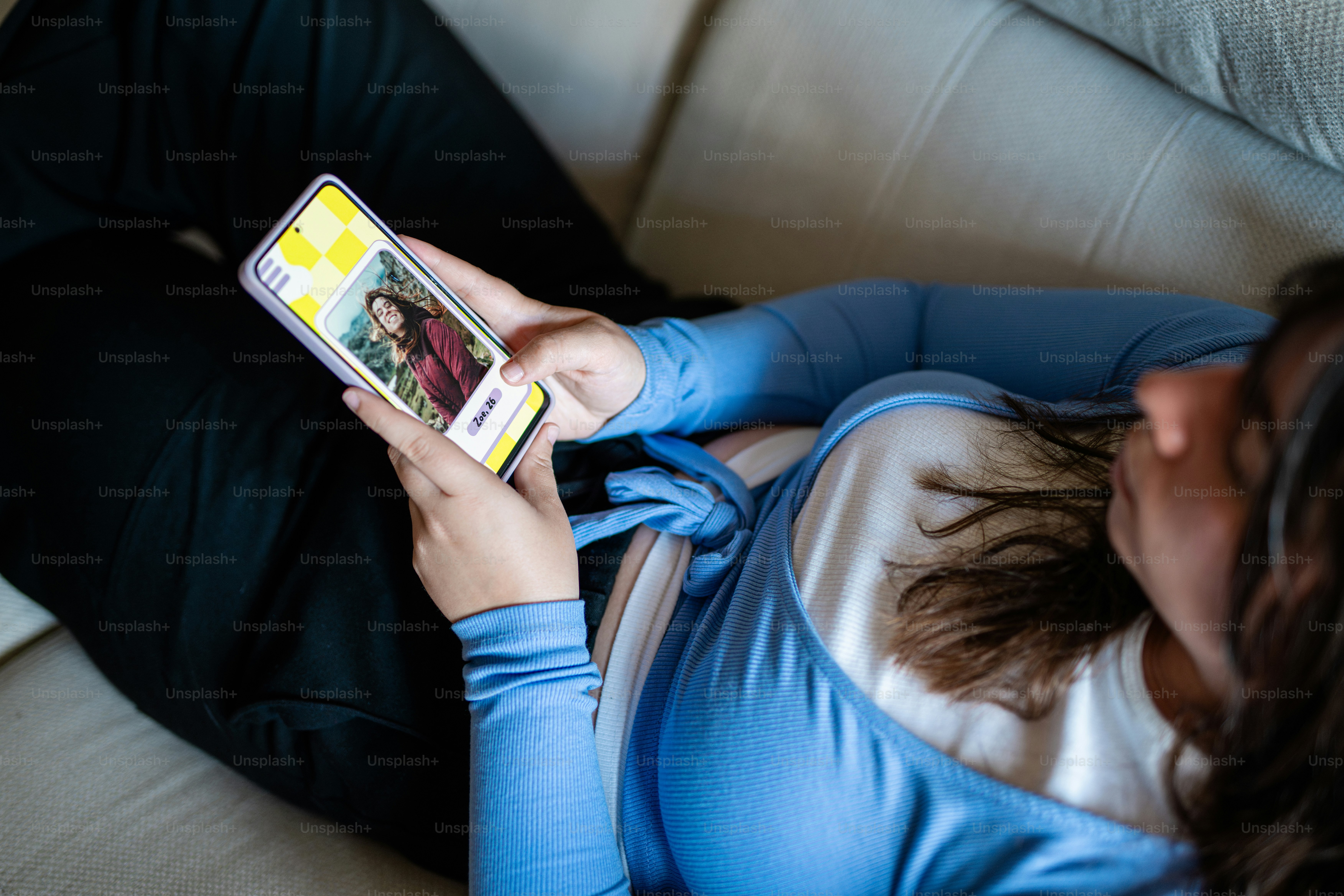 a woman laying on a couch looking at a cell phone