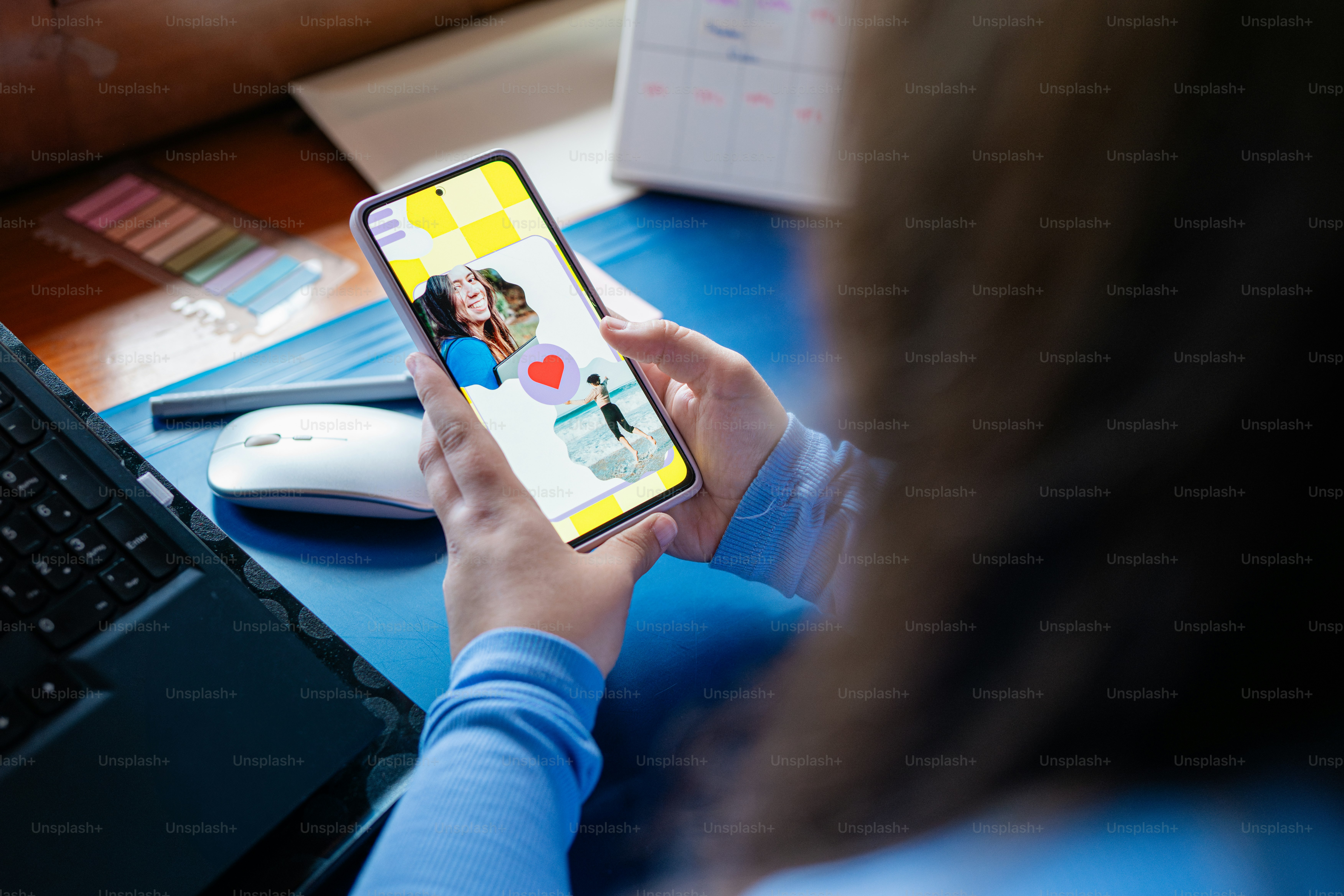 a woman sitting at a desk holding a cell phone