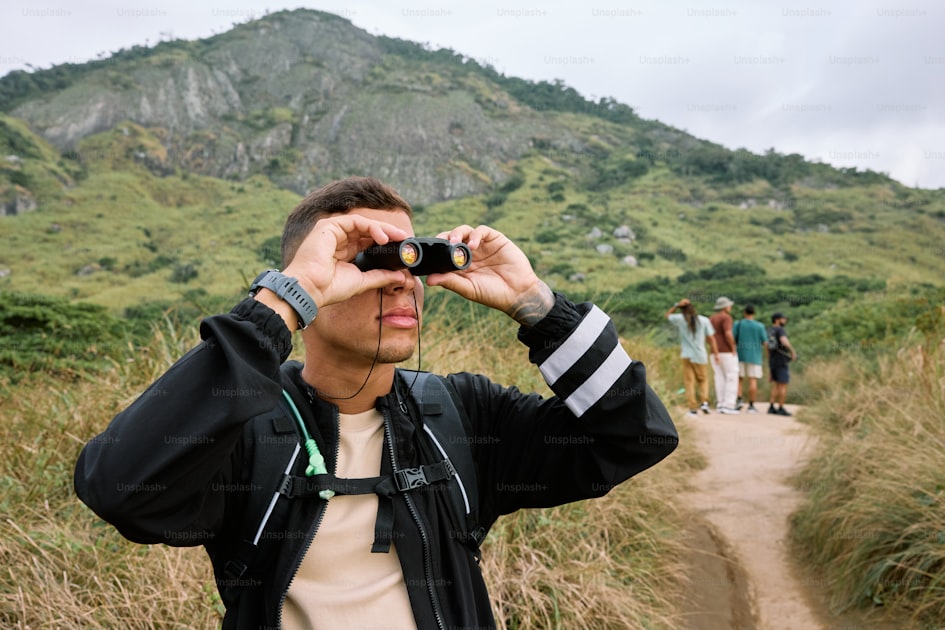 Man on a dirt road looking through binoculars, glassing for elk in open country