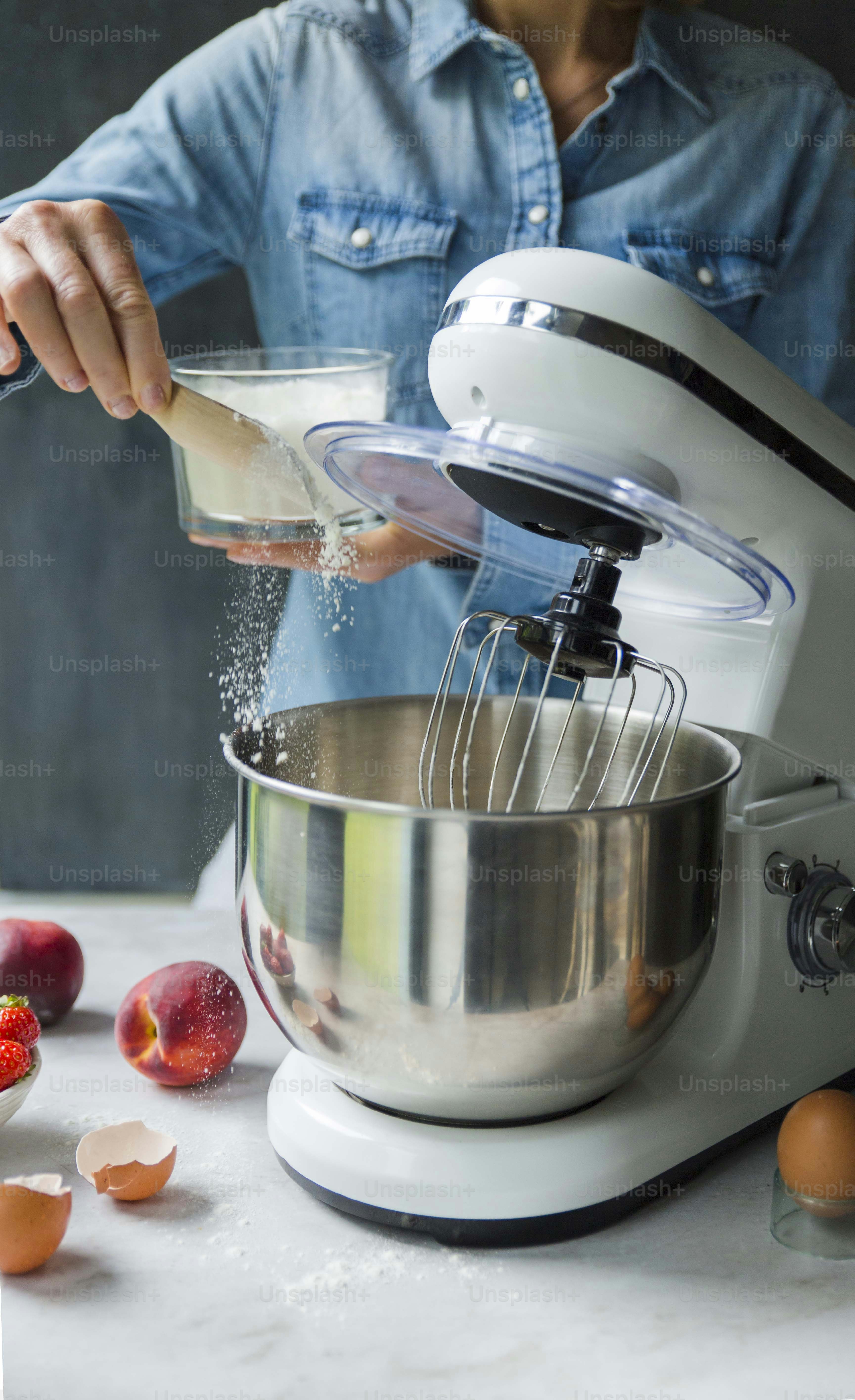 a person mixing ingredients in a mixer on a counter