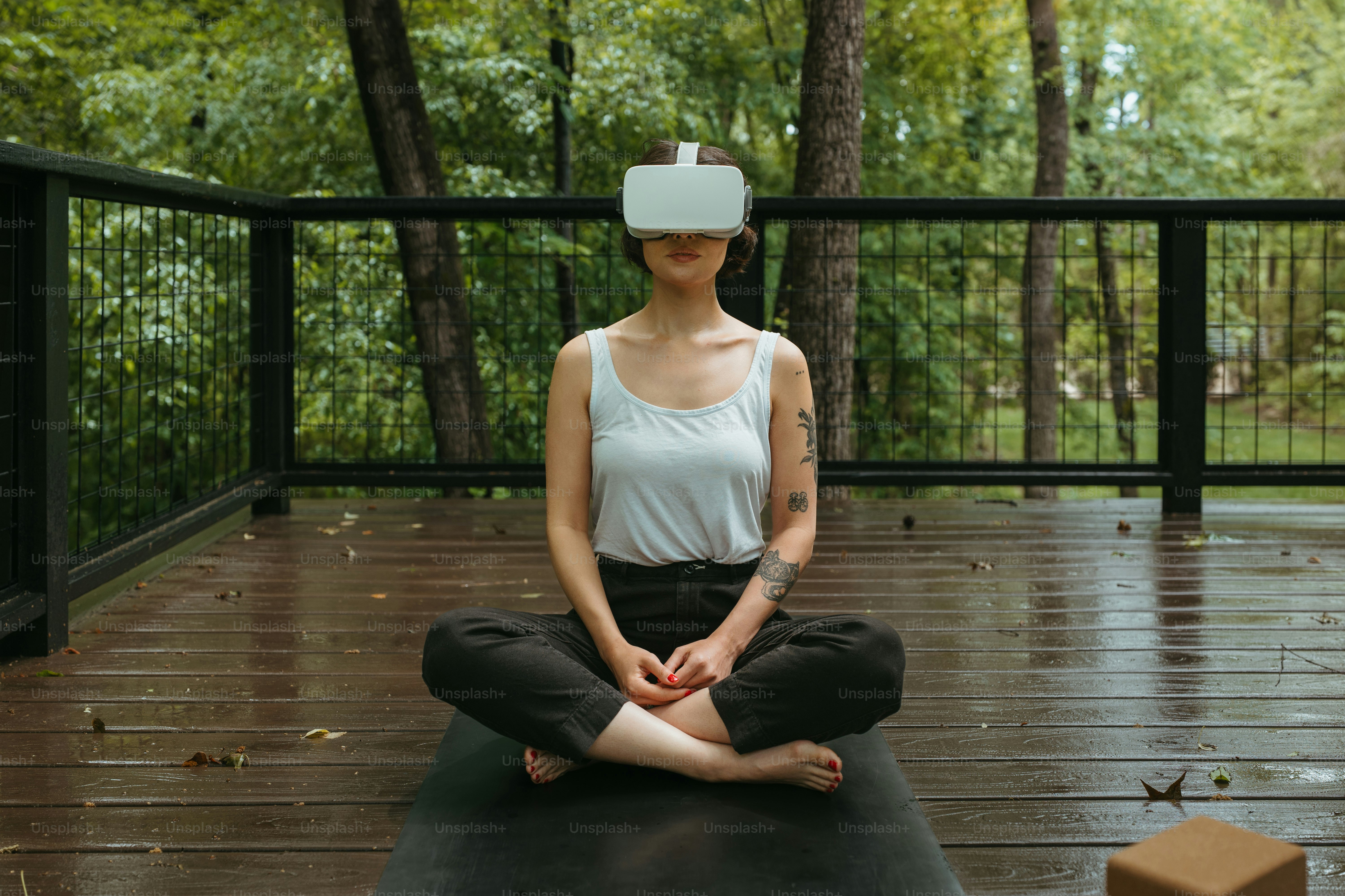 a woman sitting on a yoga mat wearing a virtual reality headset