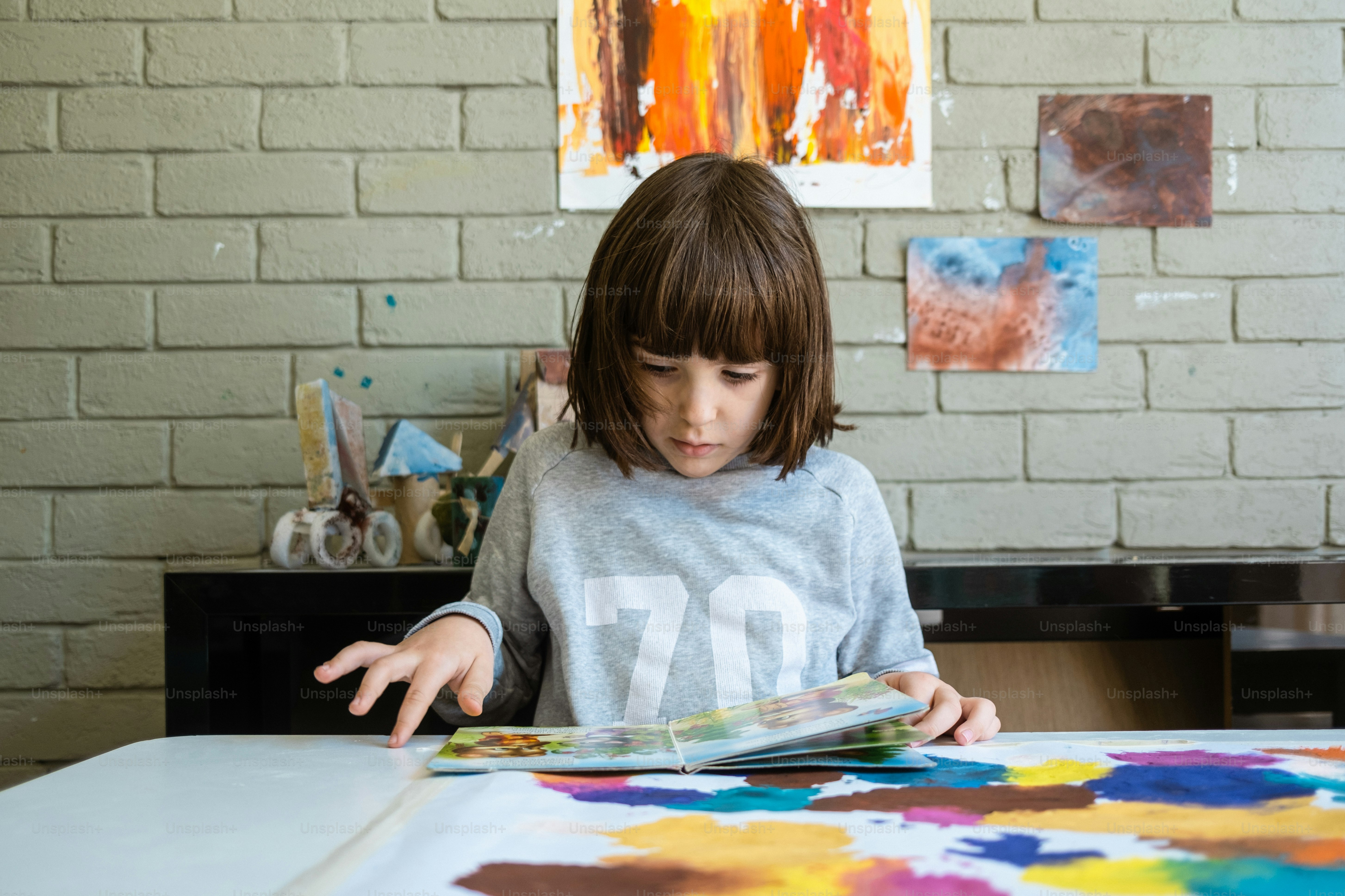una bambina seduta a un tavolo che guarda un libro