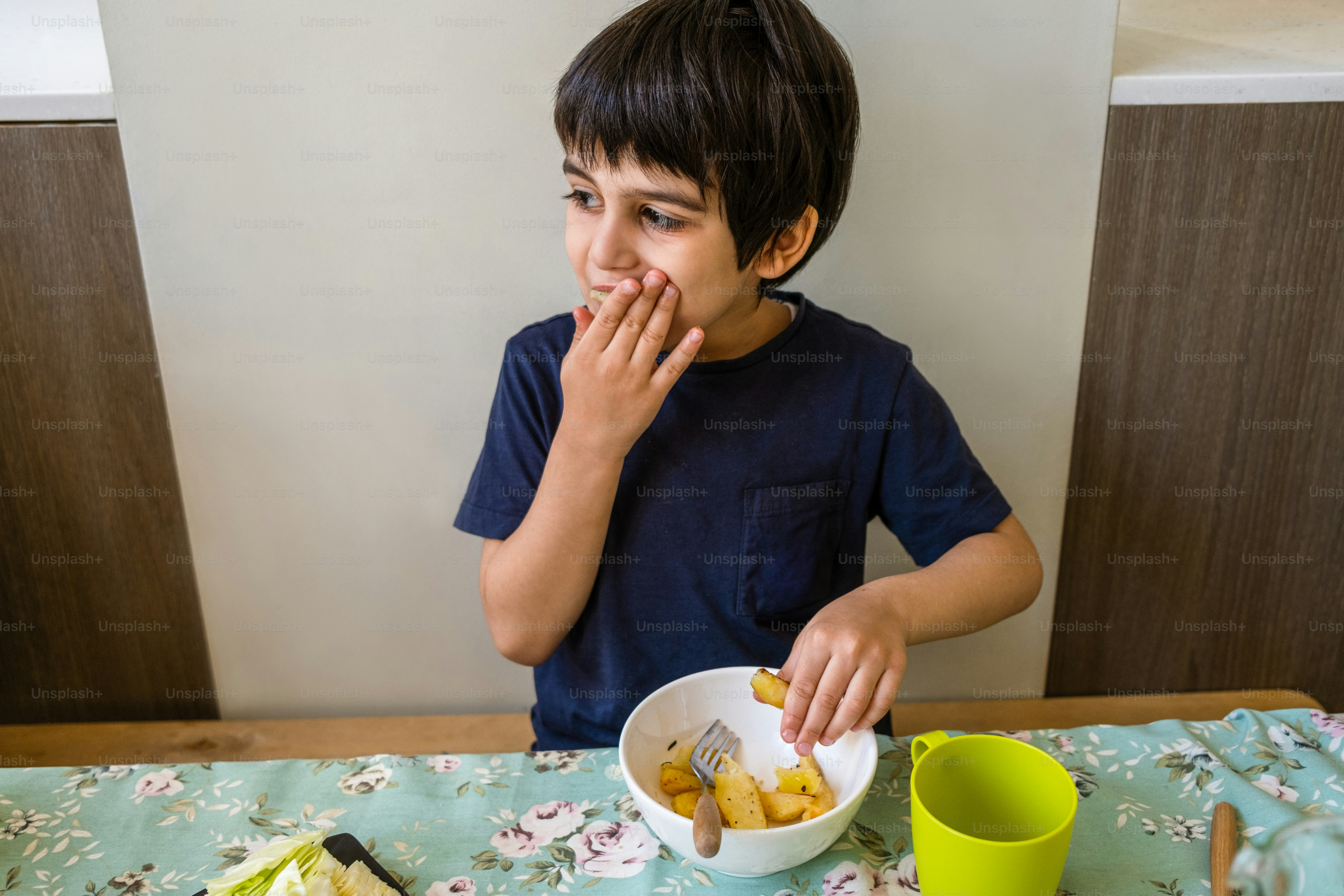 a young boy sitting at a table eating food