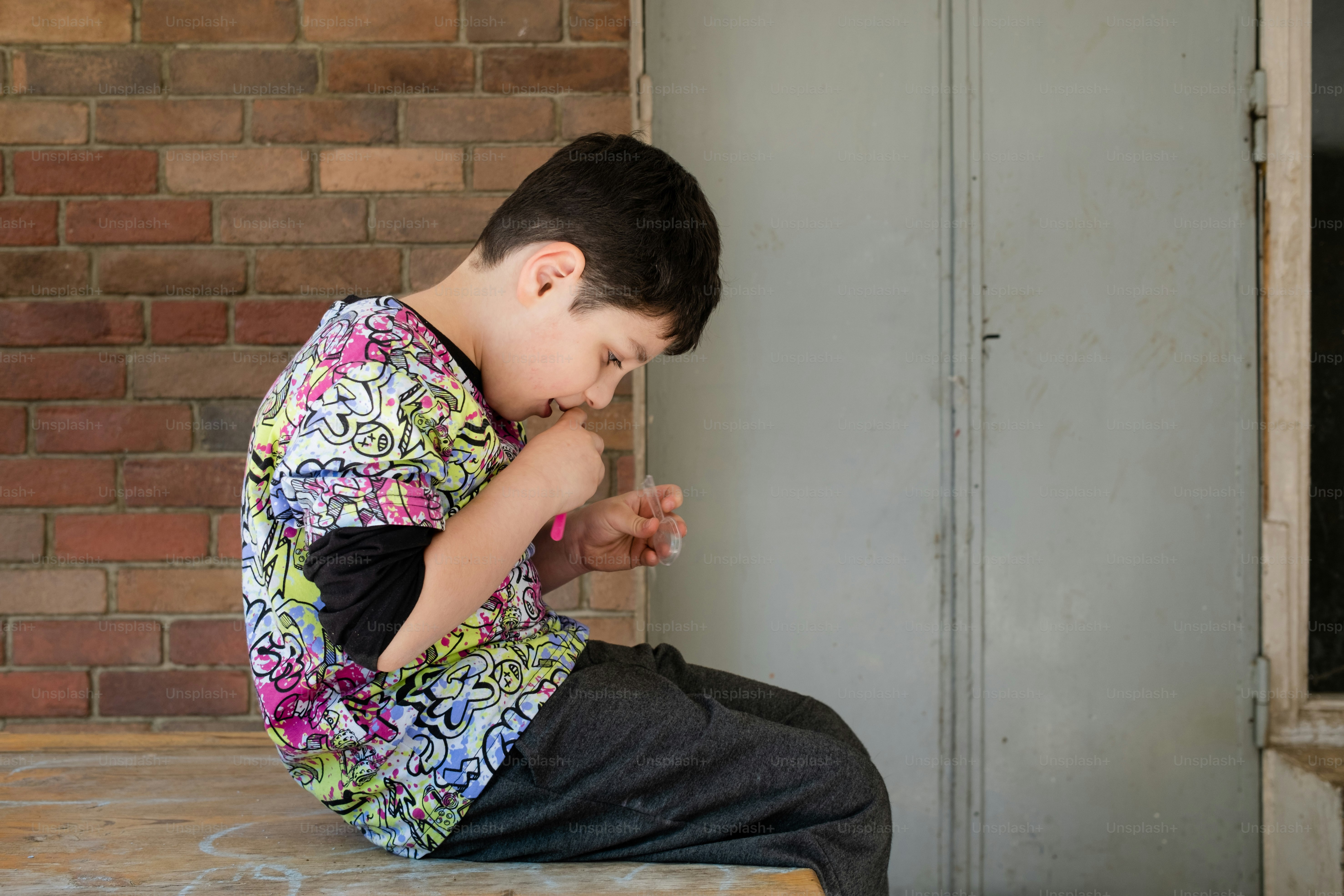 a young boy sitting on top of a wooden table