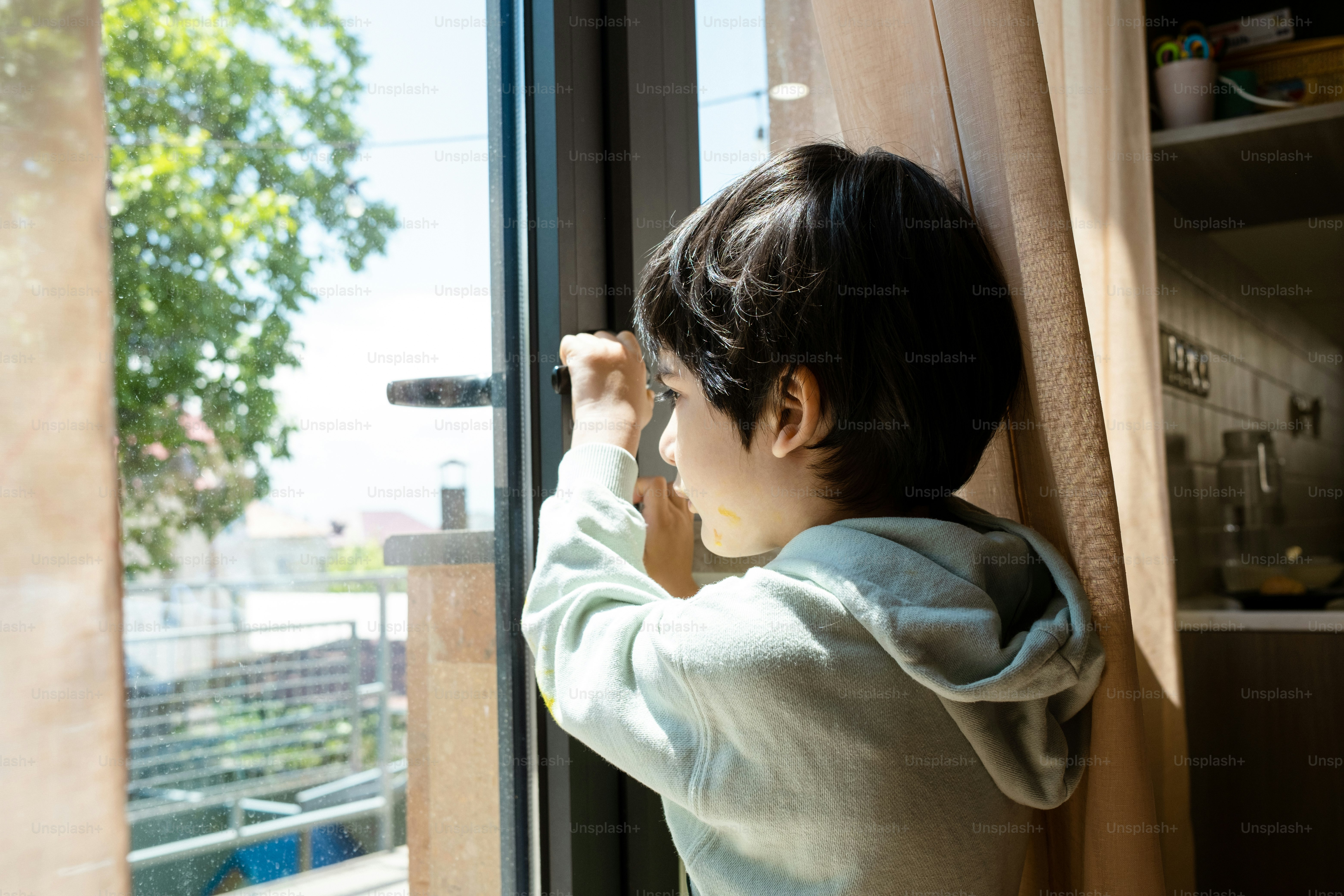 a young boy is looking out of a window