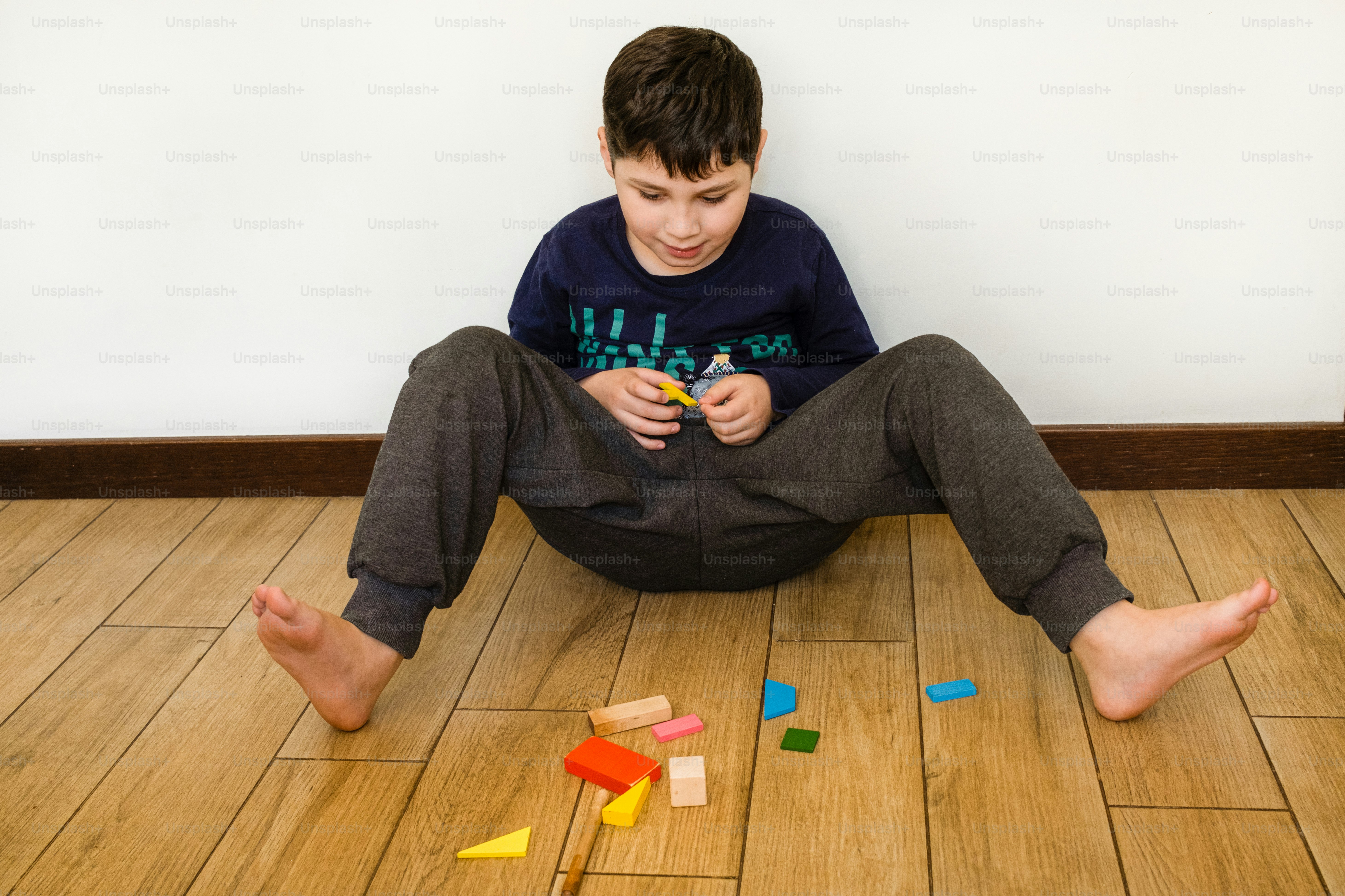 a young boy sitting on the floor playing with blocks