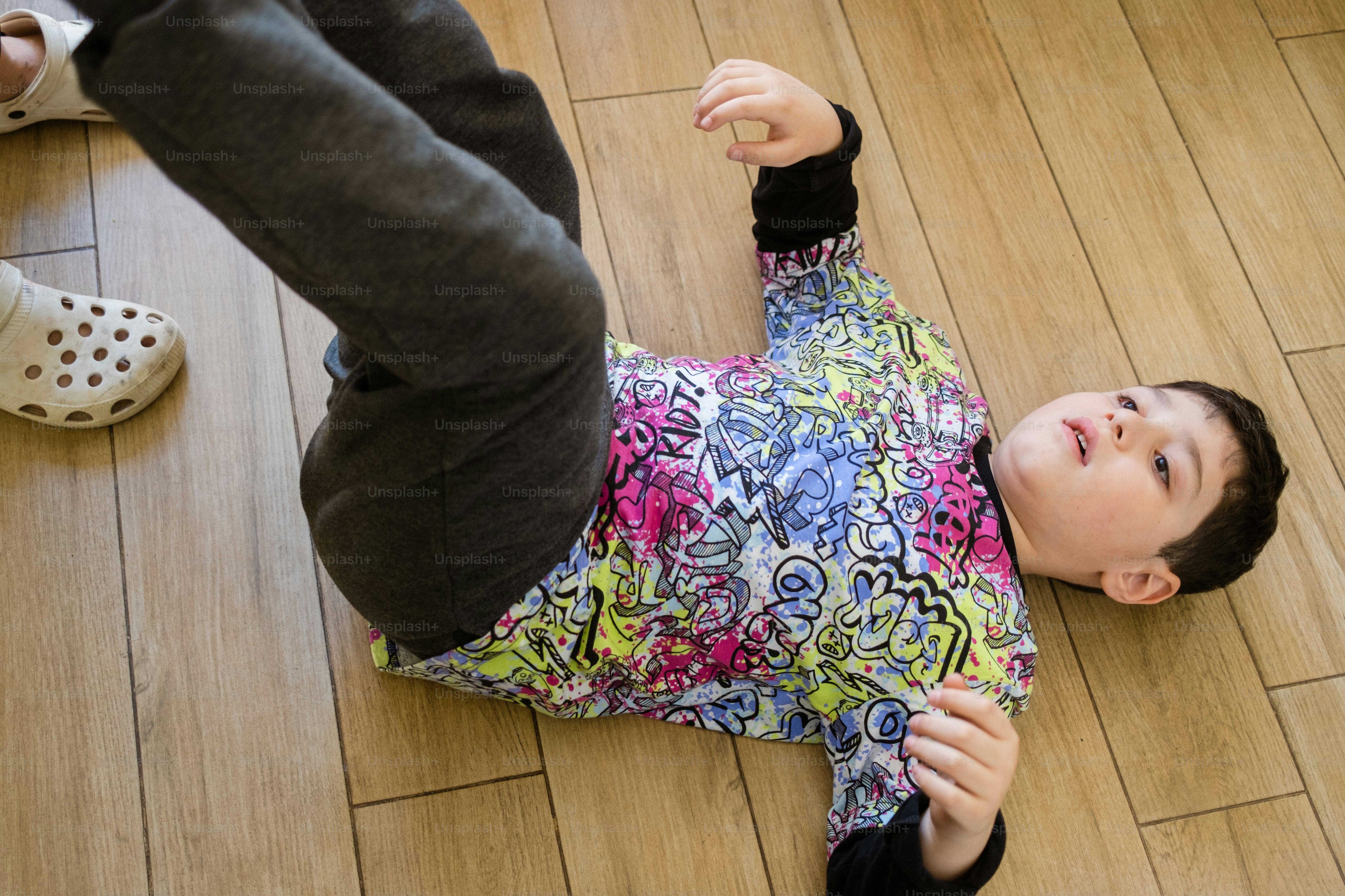 a little girl laying on the floor with her hands in the air
