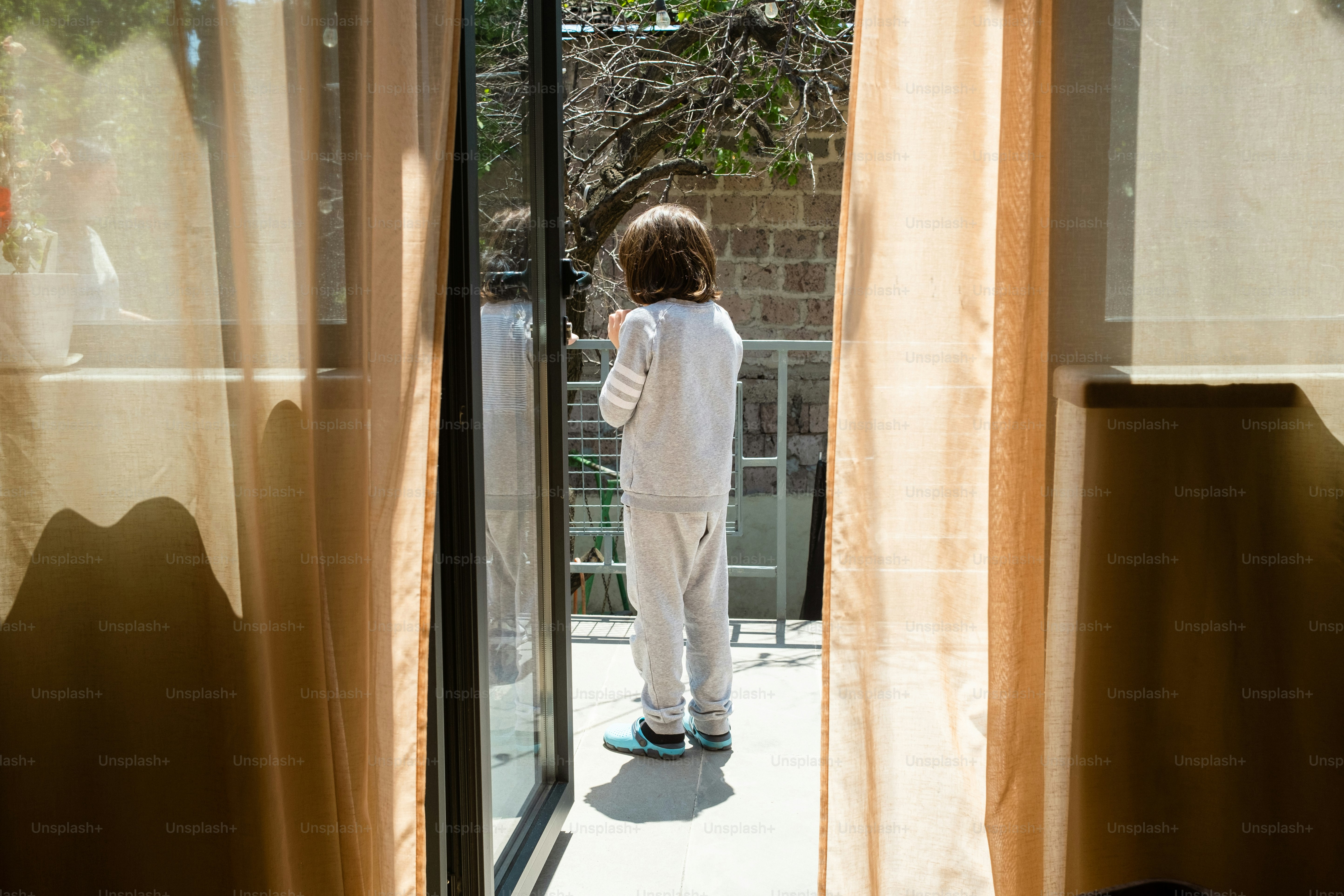 a little boy standing in front of a sliding glass door