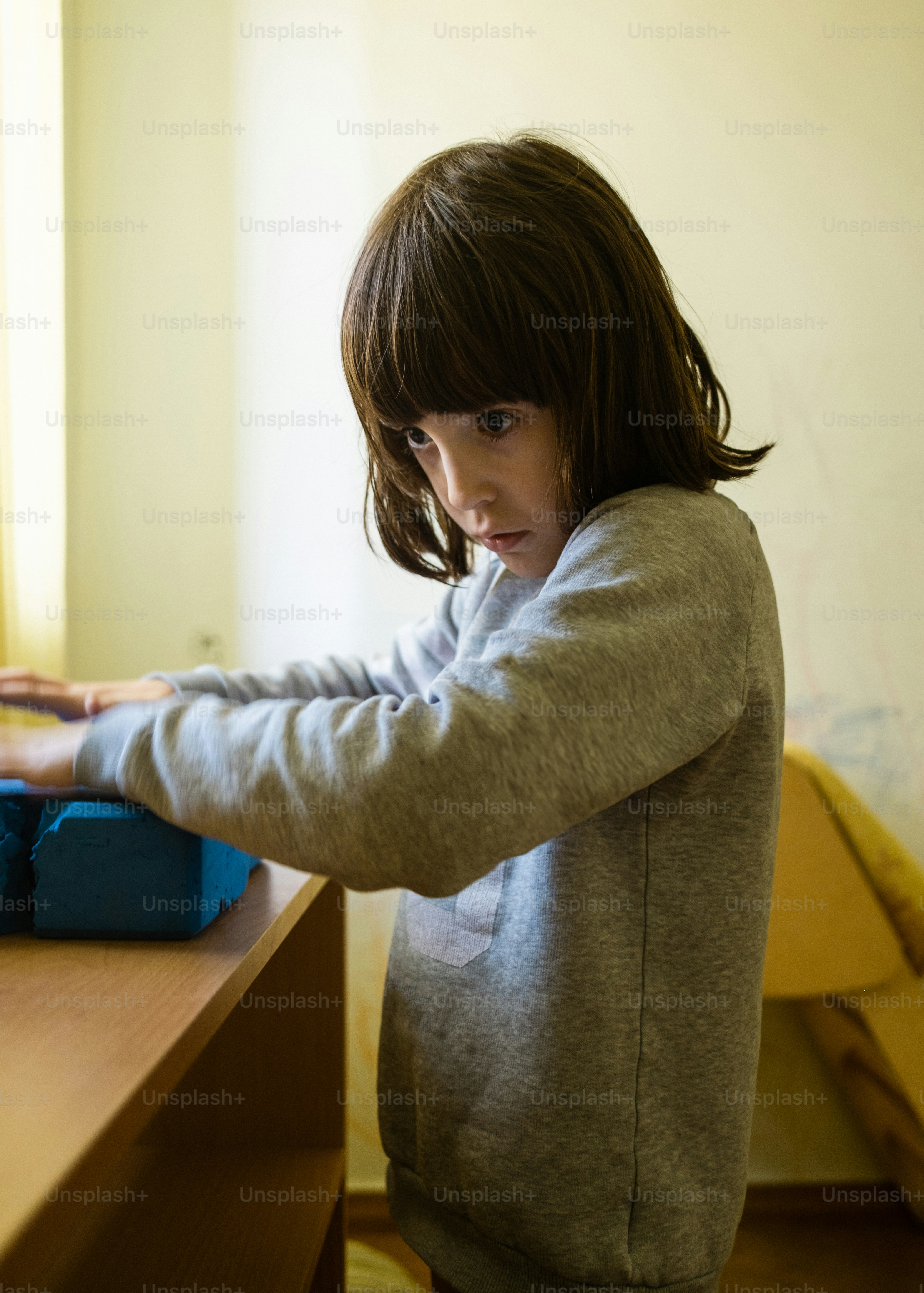 a young girl standing at a desk with a laptop