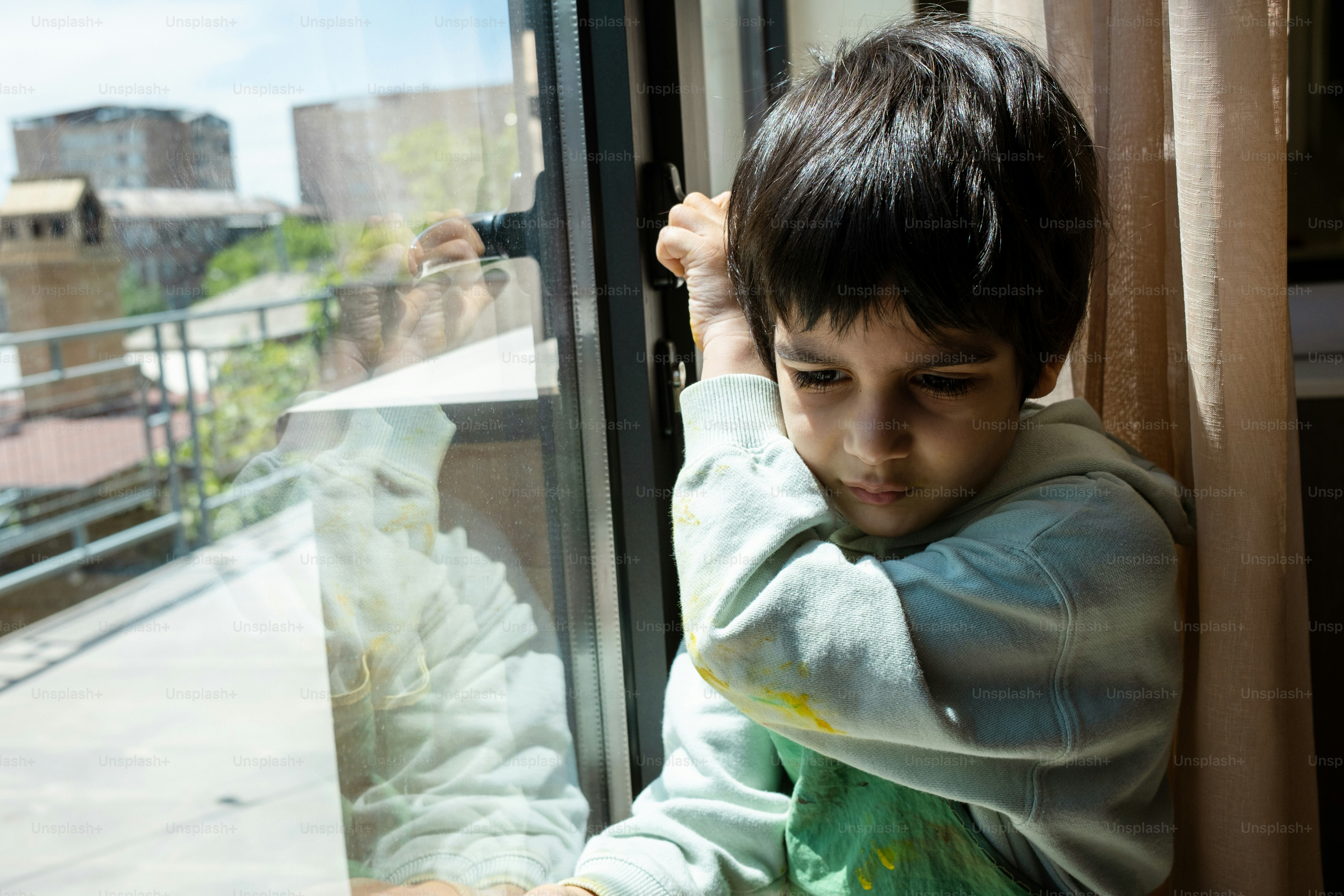 a young boy is looking out a window