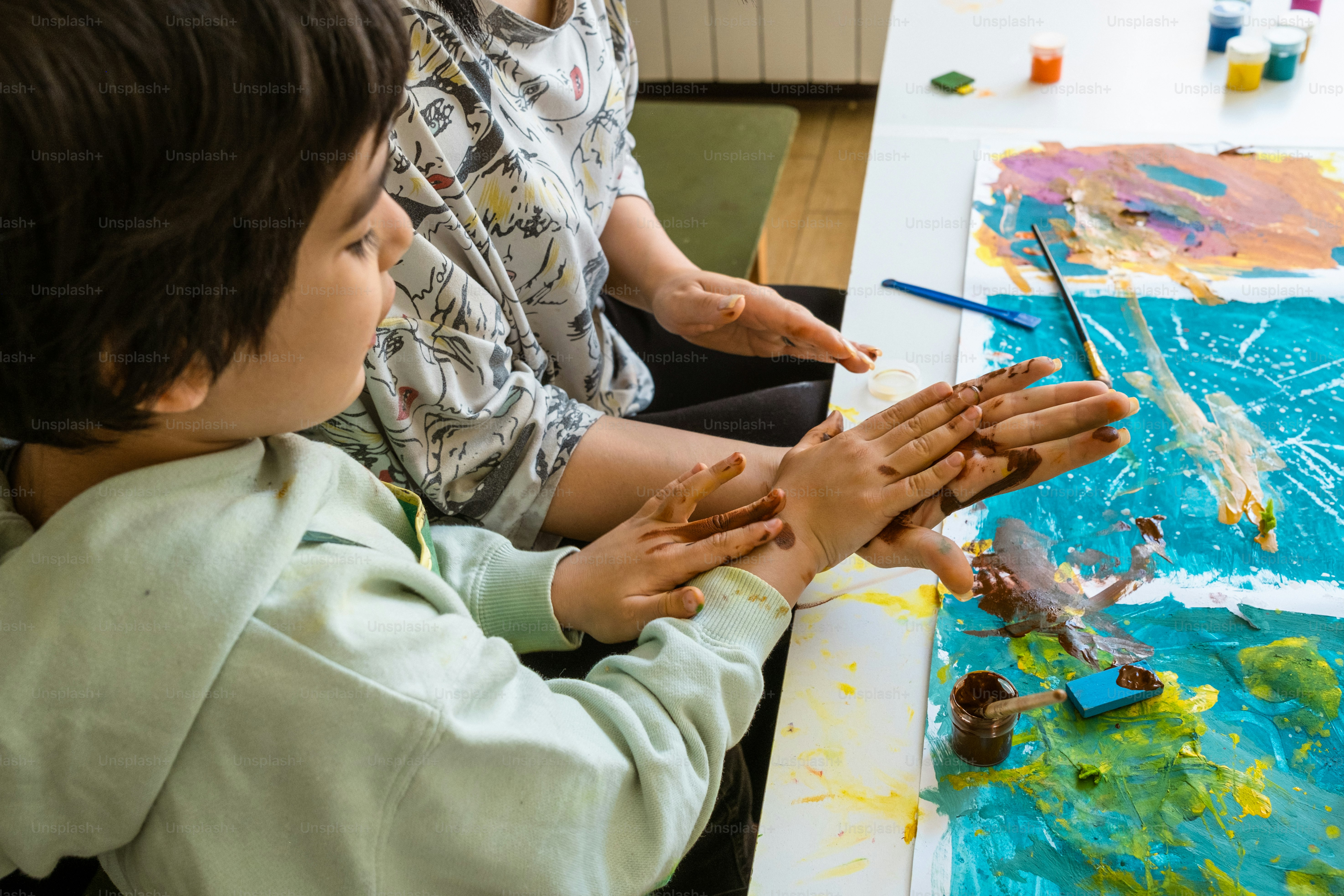 a couple of kids sitting at a table with paint