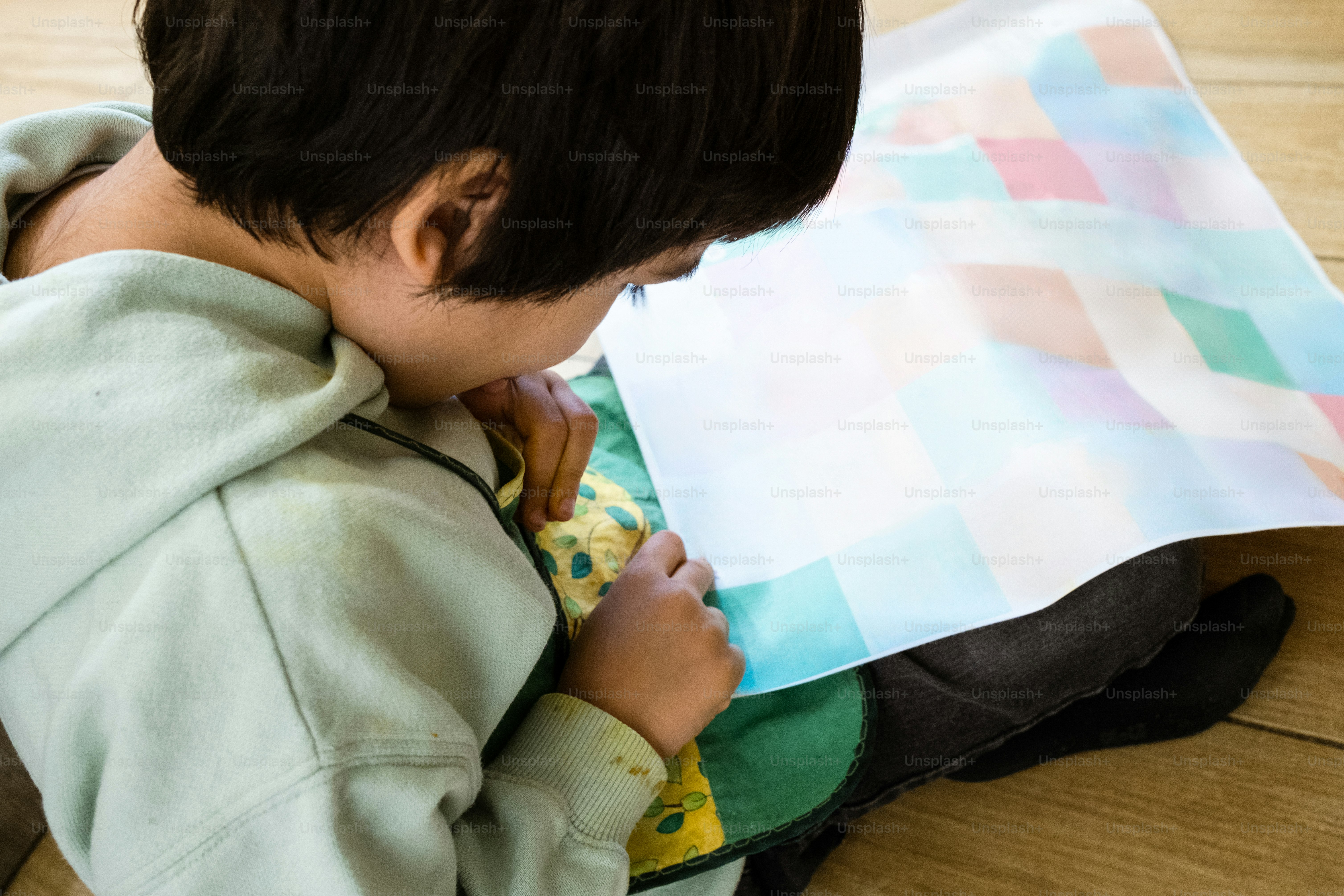 ein kleiner Junge, der mit einem Blatt Papier auf dem Boden sitzt