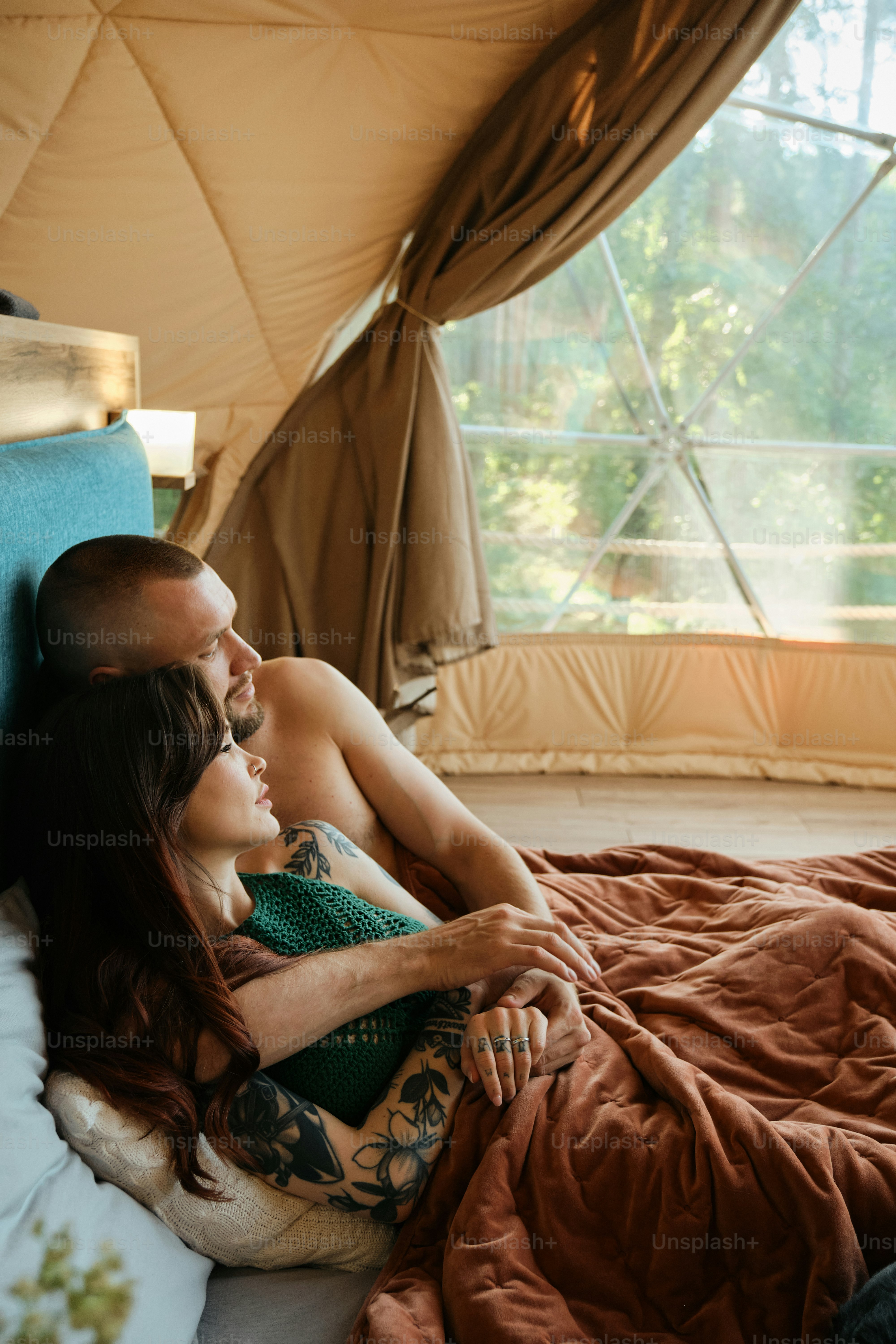 un homme et une femme allongés sur un lit dans une tente