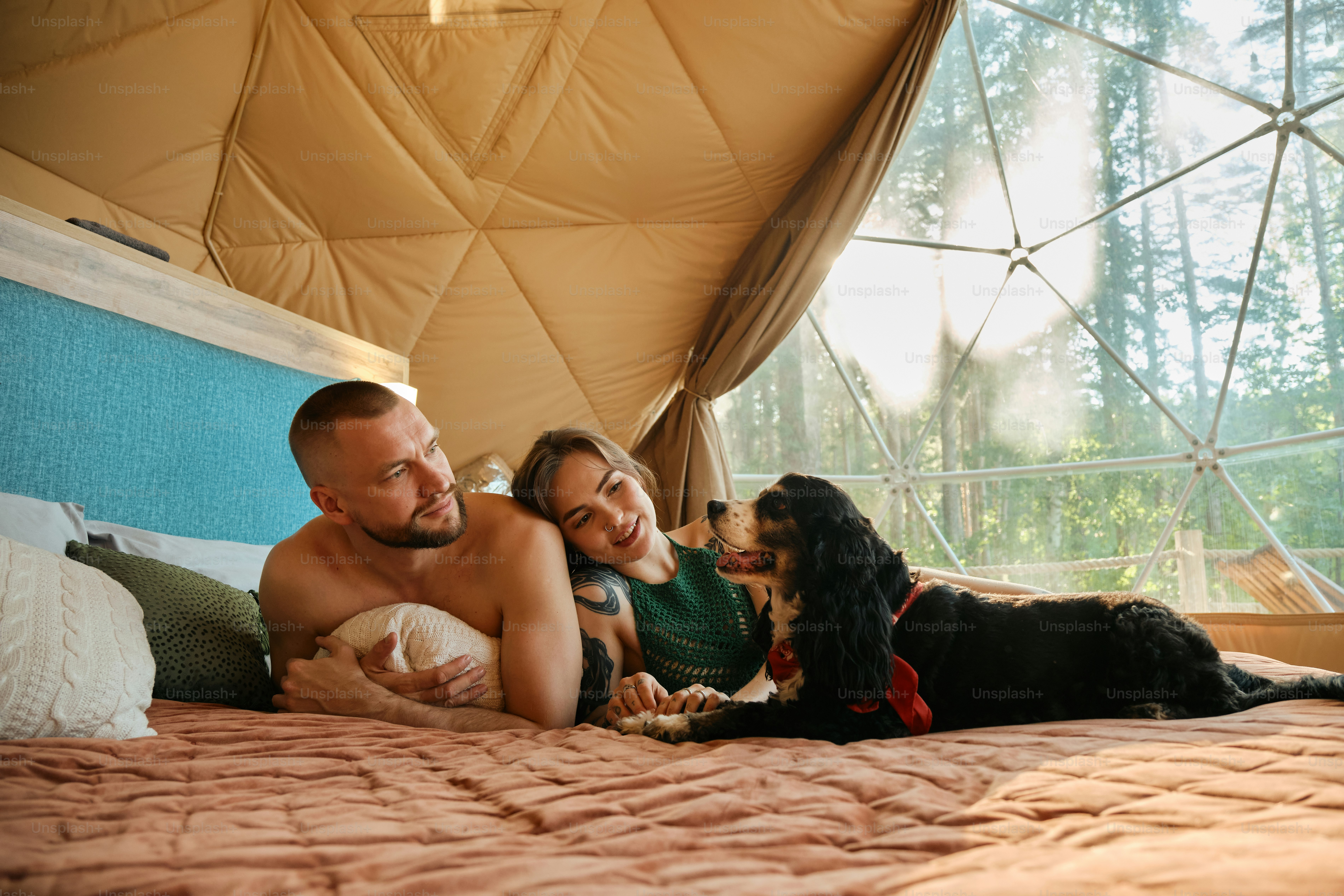 un homme et une femme allongés sur un lit avec un chien